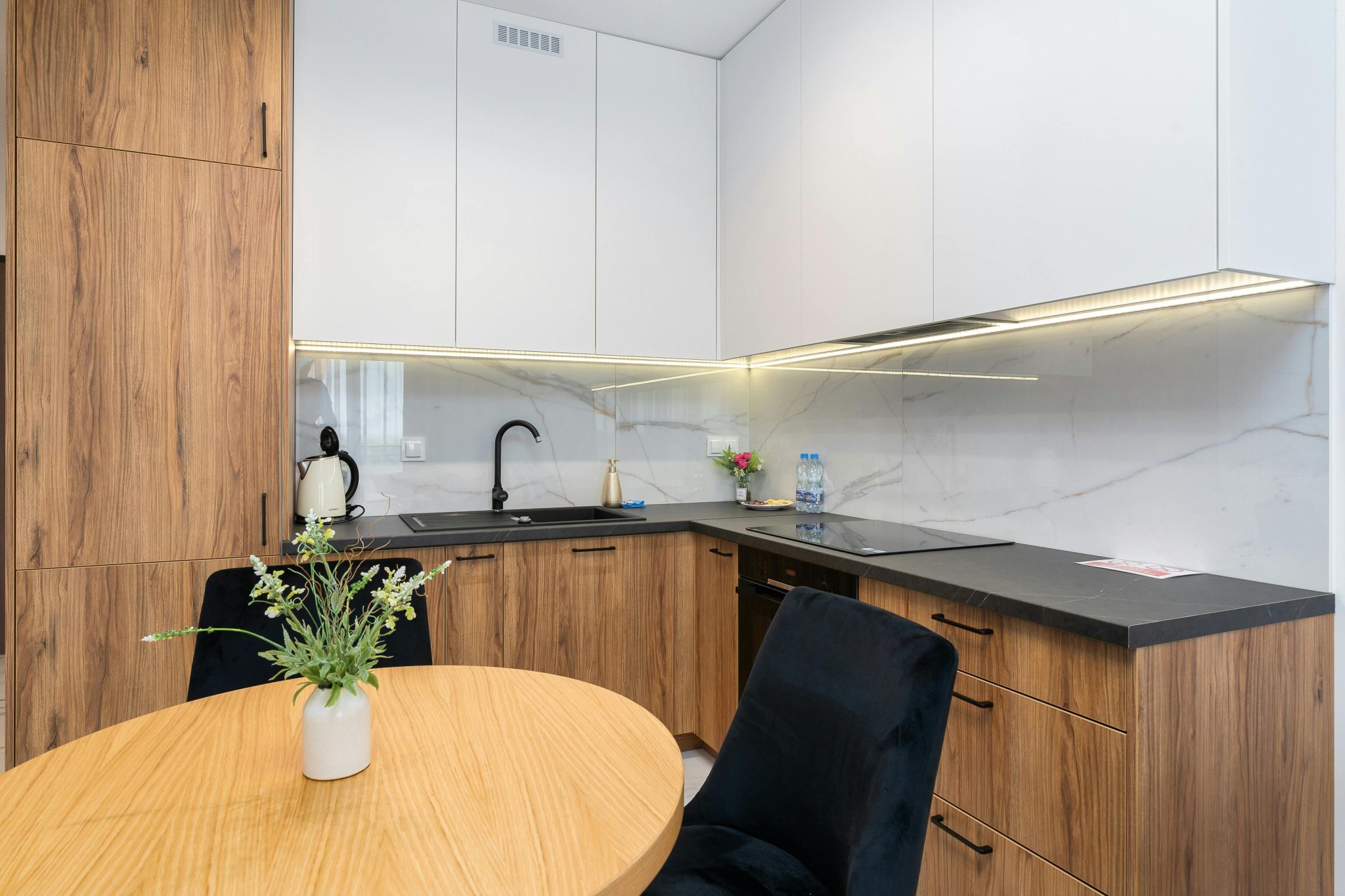 Contemporary kitchen space featuring wooden cabinets, marble backsplash, and sleek design.