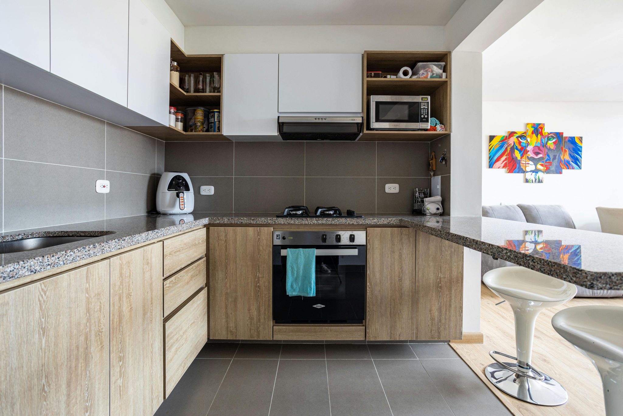 Contemporary kitchen with wood cabinets and integrated appliances in Bogotá home.