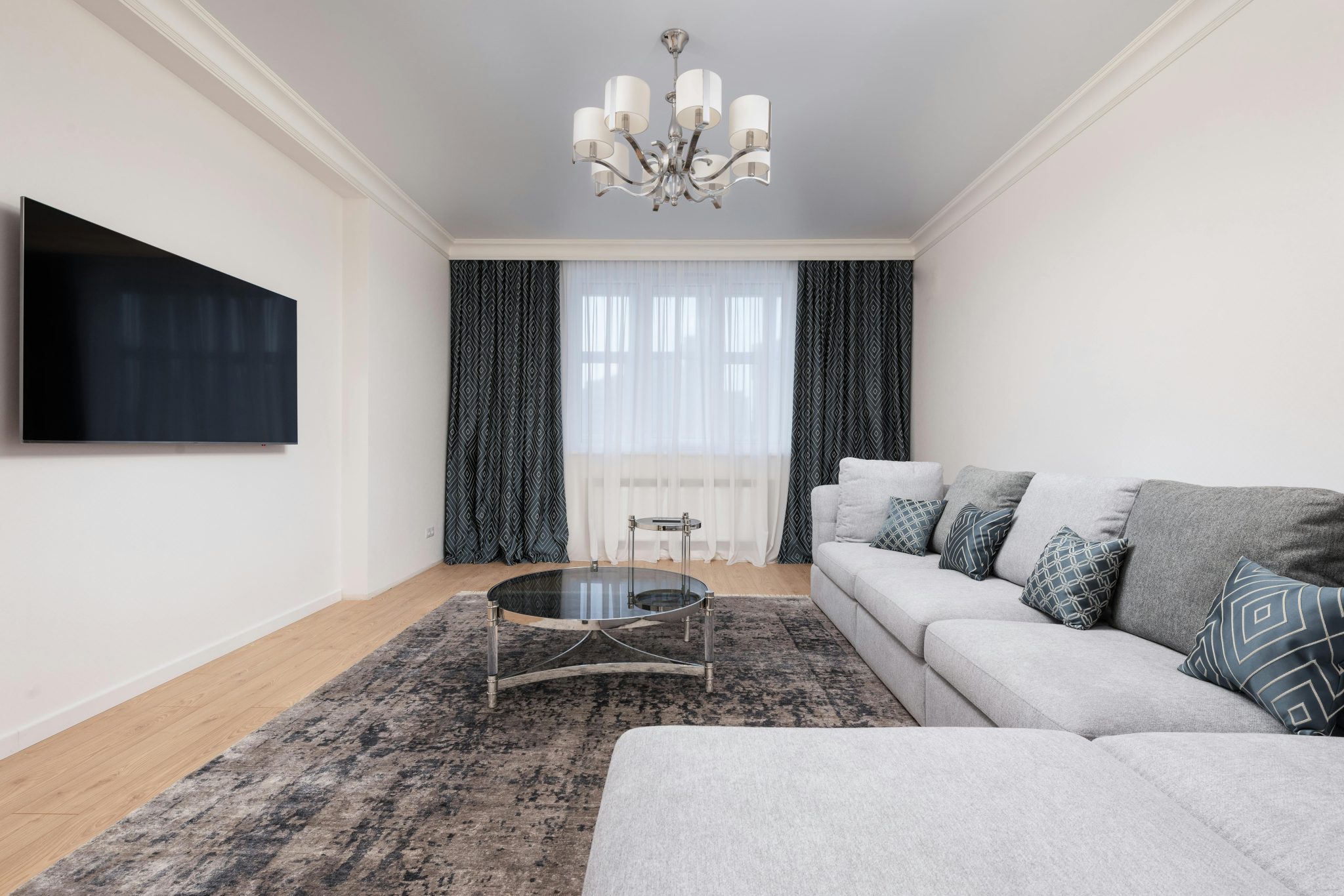 Contemporary living room with decorative cushions on sofa against table and TV with black screen in house