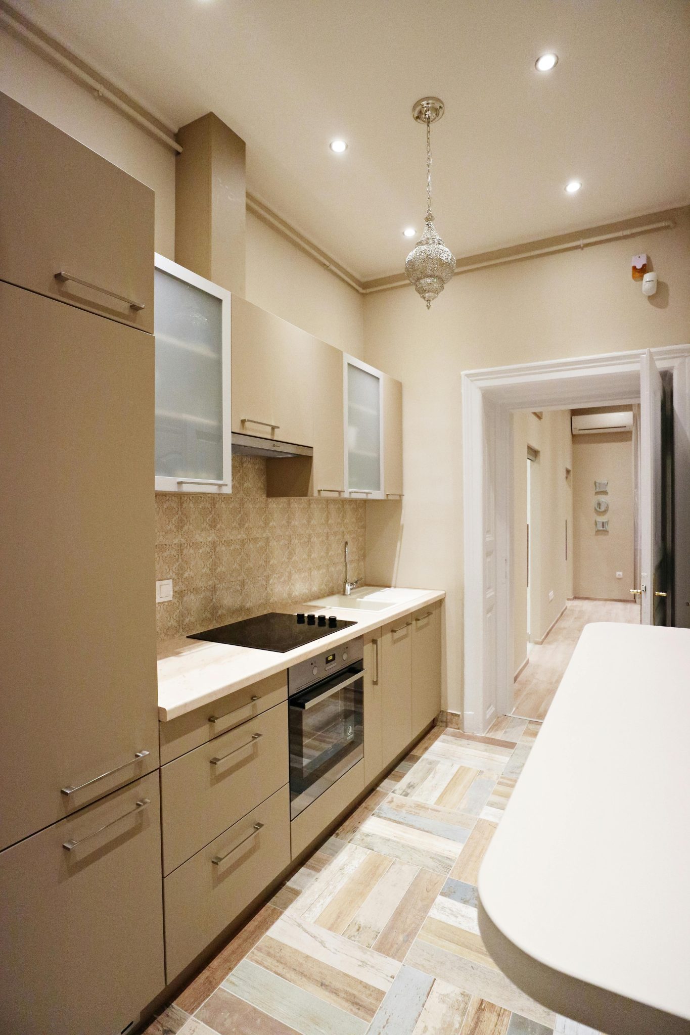 Contemporary small kitchen with beige cabinets and patterned flooring.