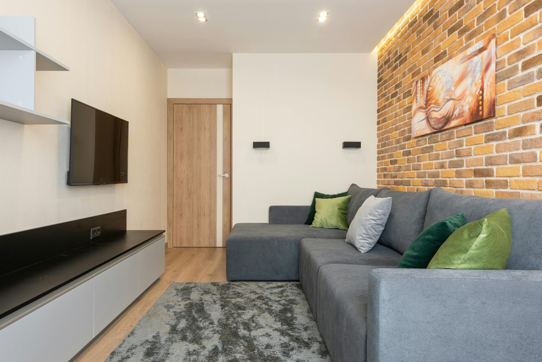 Cozy modern living room with brick wall and gray sofa, perfect for relaxation.