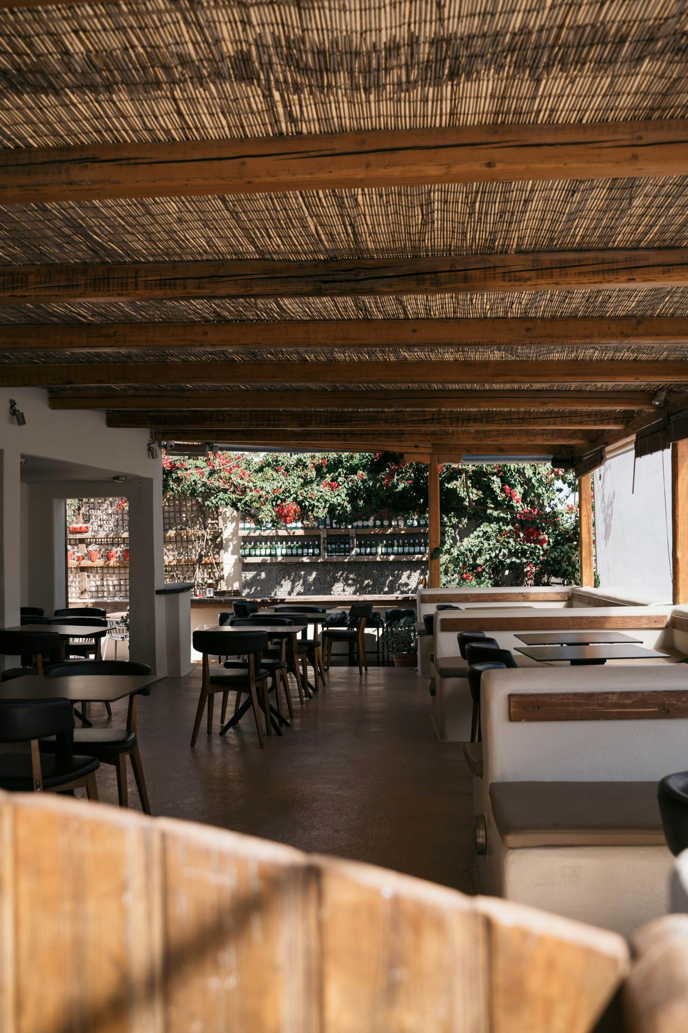 Cozy open-air restaurant with natural wooden decor in a sunny tropical setting.