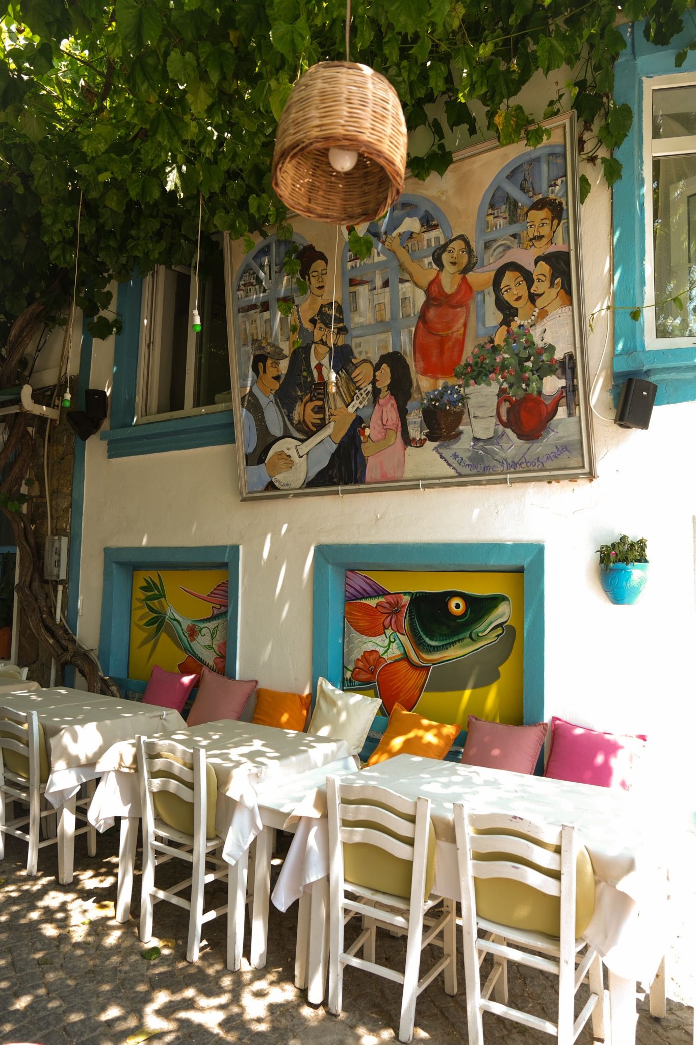 Cozy outdoor cafe setting with colorful murals and shaded seating.