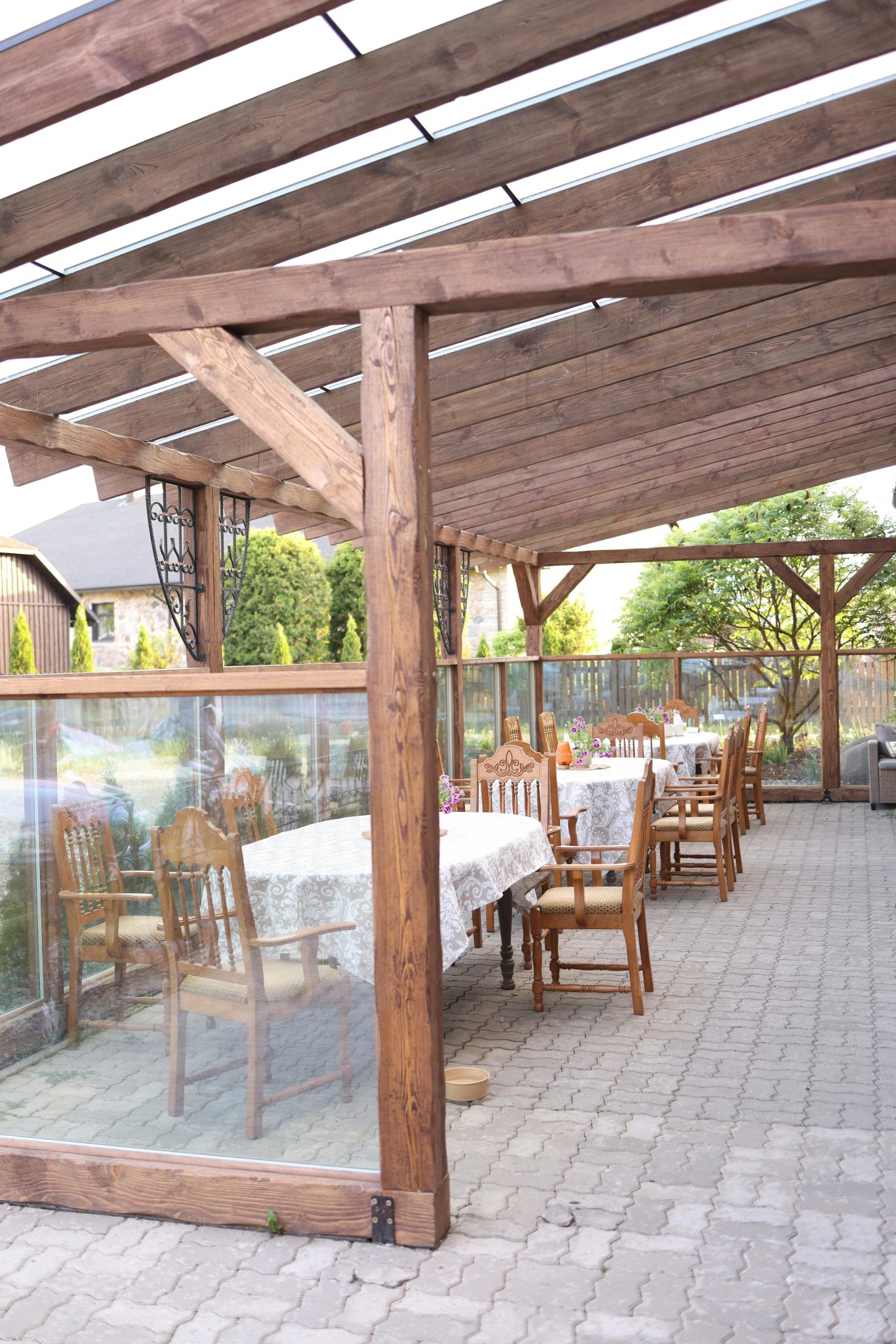 Cozy outdoor terrace with wooden roof, tables, and white tablecloths. Ideal for dining.