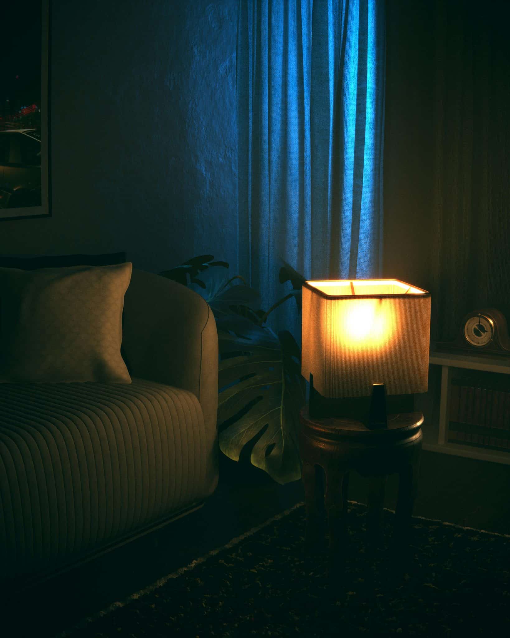 Dimly lit cozy living room featuring a sofa, lamp, and curtains, perfect for relaxation ambiance.