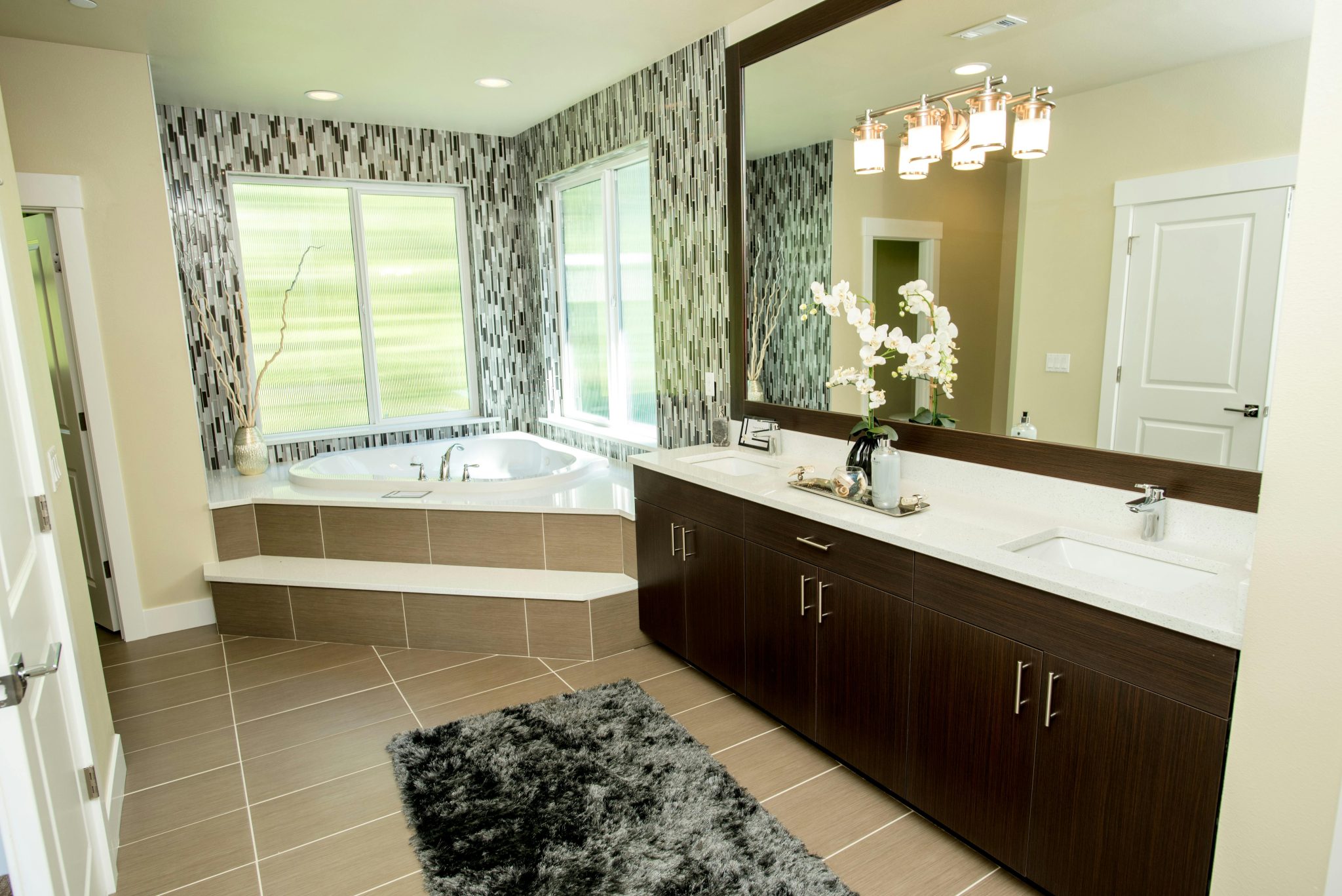 Elegant bathroom featuring a large mirror, jacuzzi tub, and double sink vanity.