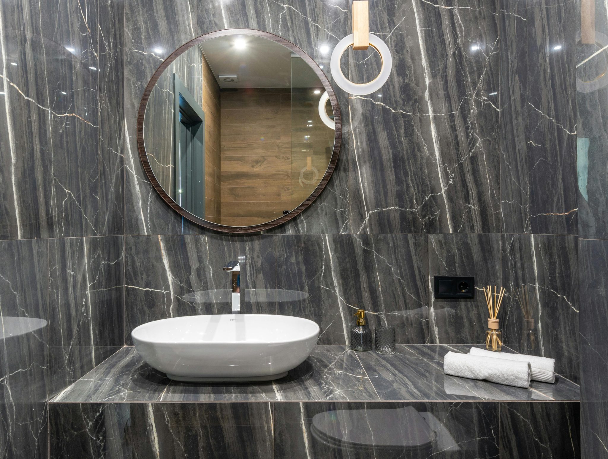 Elegant bathroom featuring a modern sink, round mirror, and marble finishes.