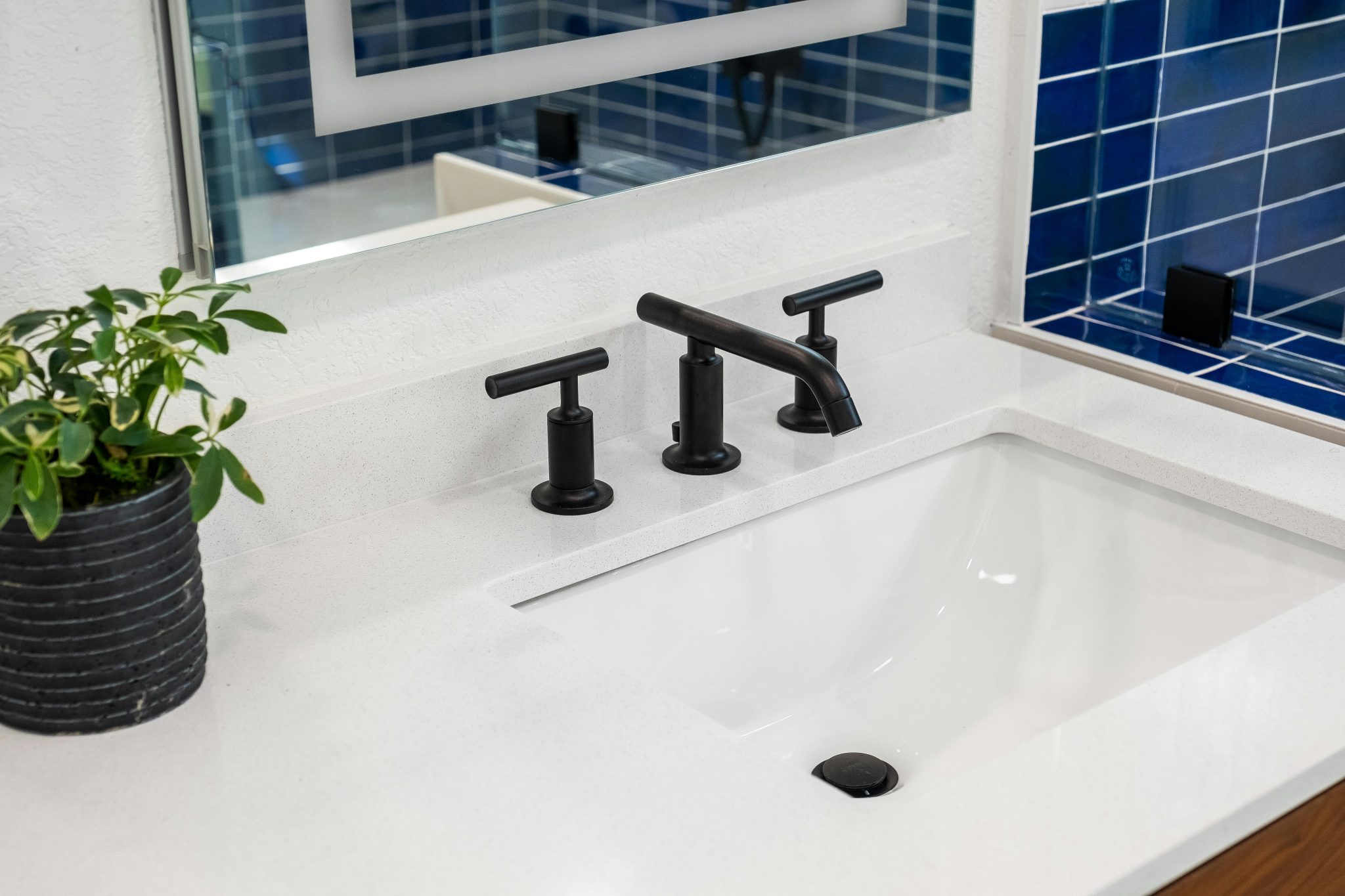 Elegant bathroom sink with black faucet and plant. Interior design inspiration.