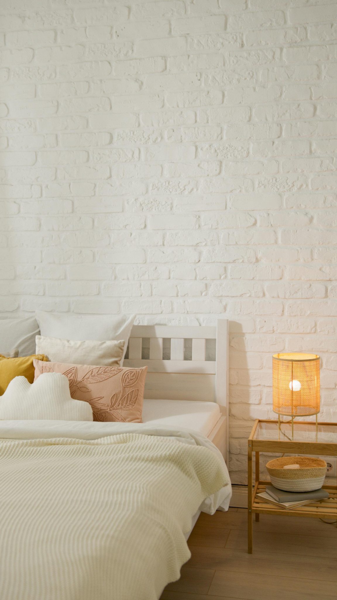 Elegant bedroom featuring a comfortable bed, pillows, side table, and warm bedside lamp.