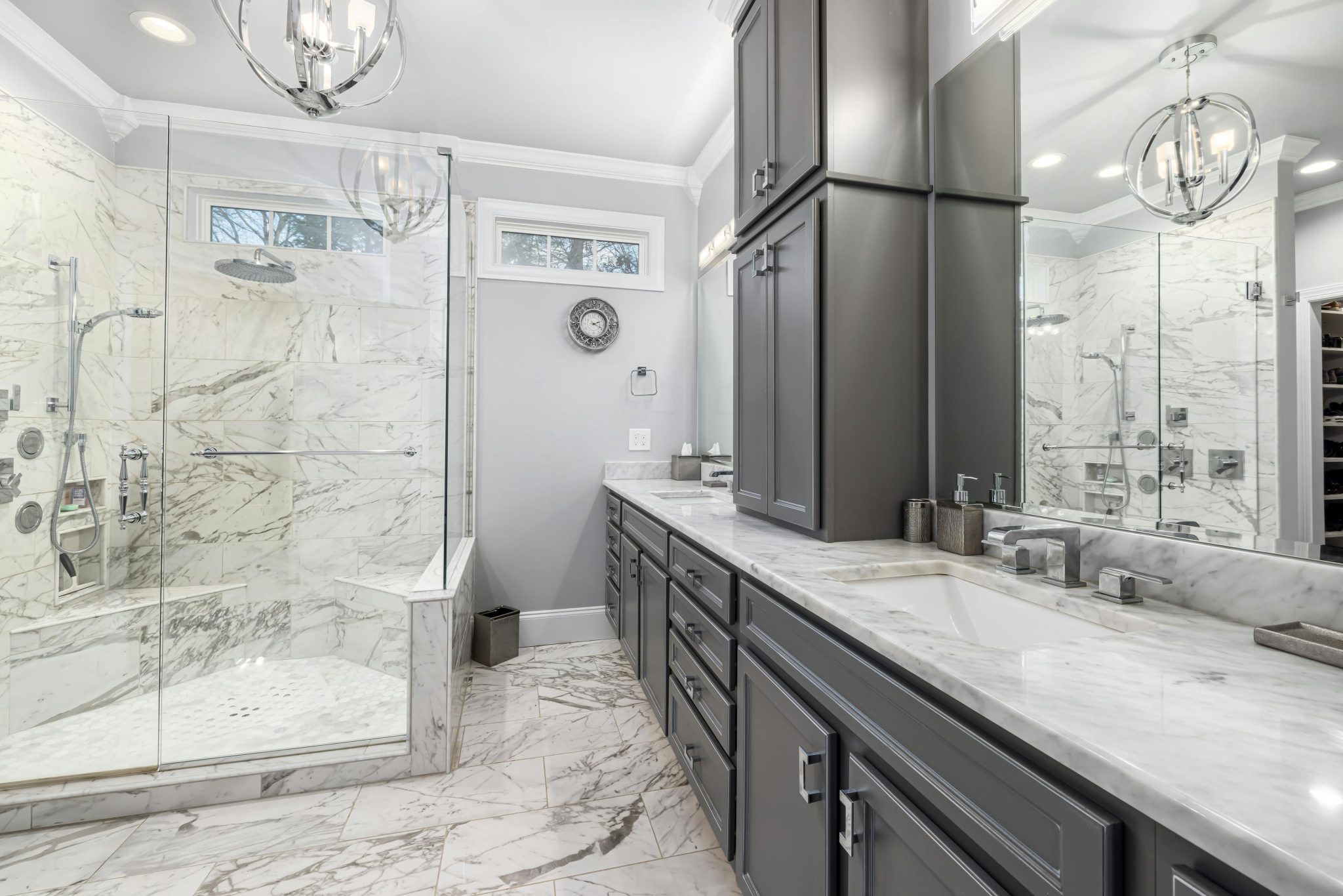 Elegant contemporary bathroom with marble surfaces and gray cabinets.
