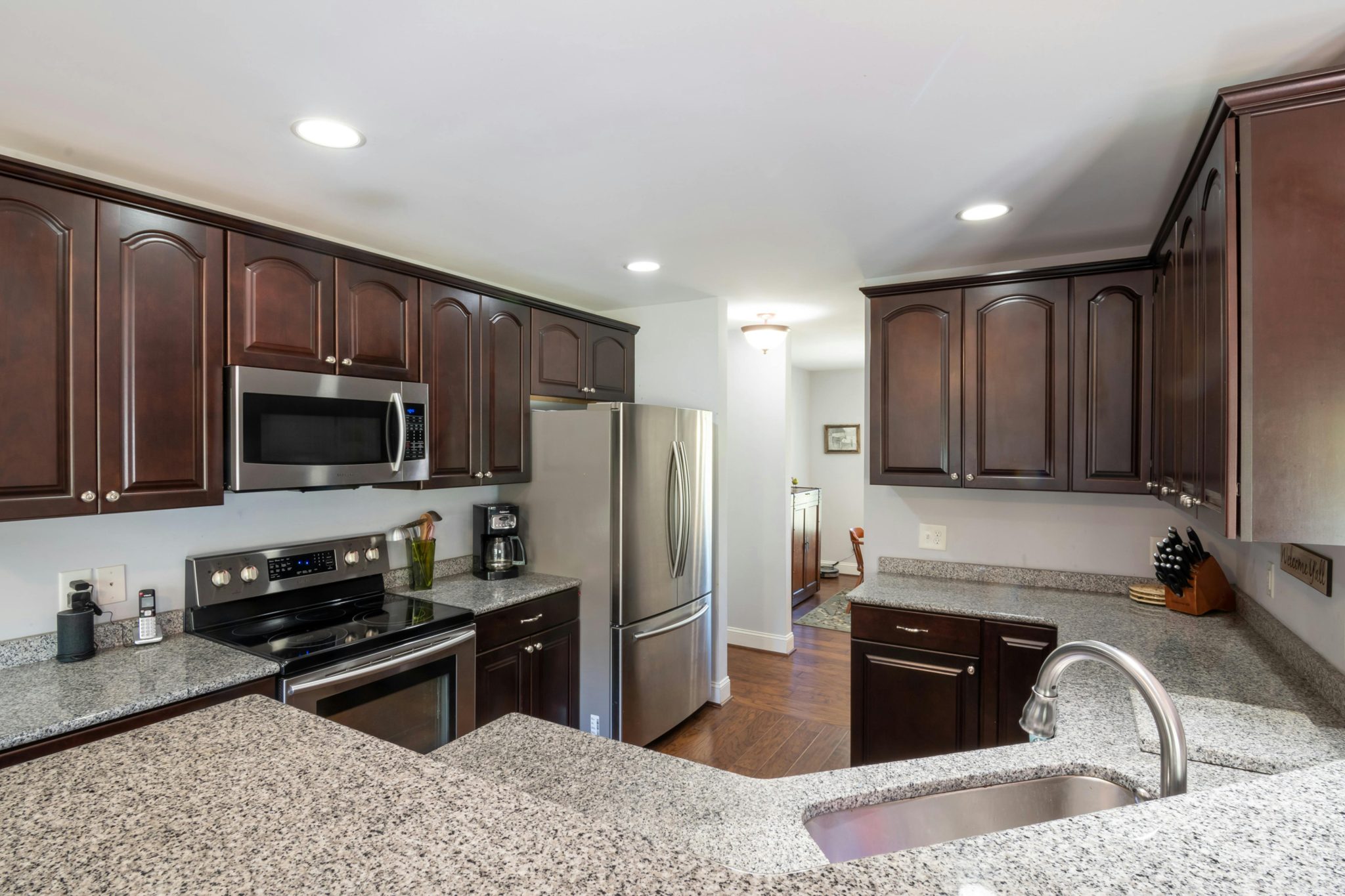 Elegant kitchen featuring dark wooden cabinets, granite countertops, and stainless steel appliances in a contemporary setting.