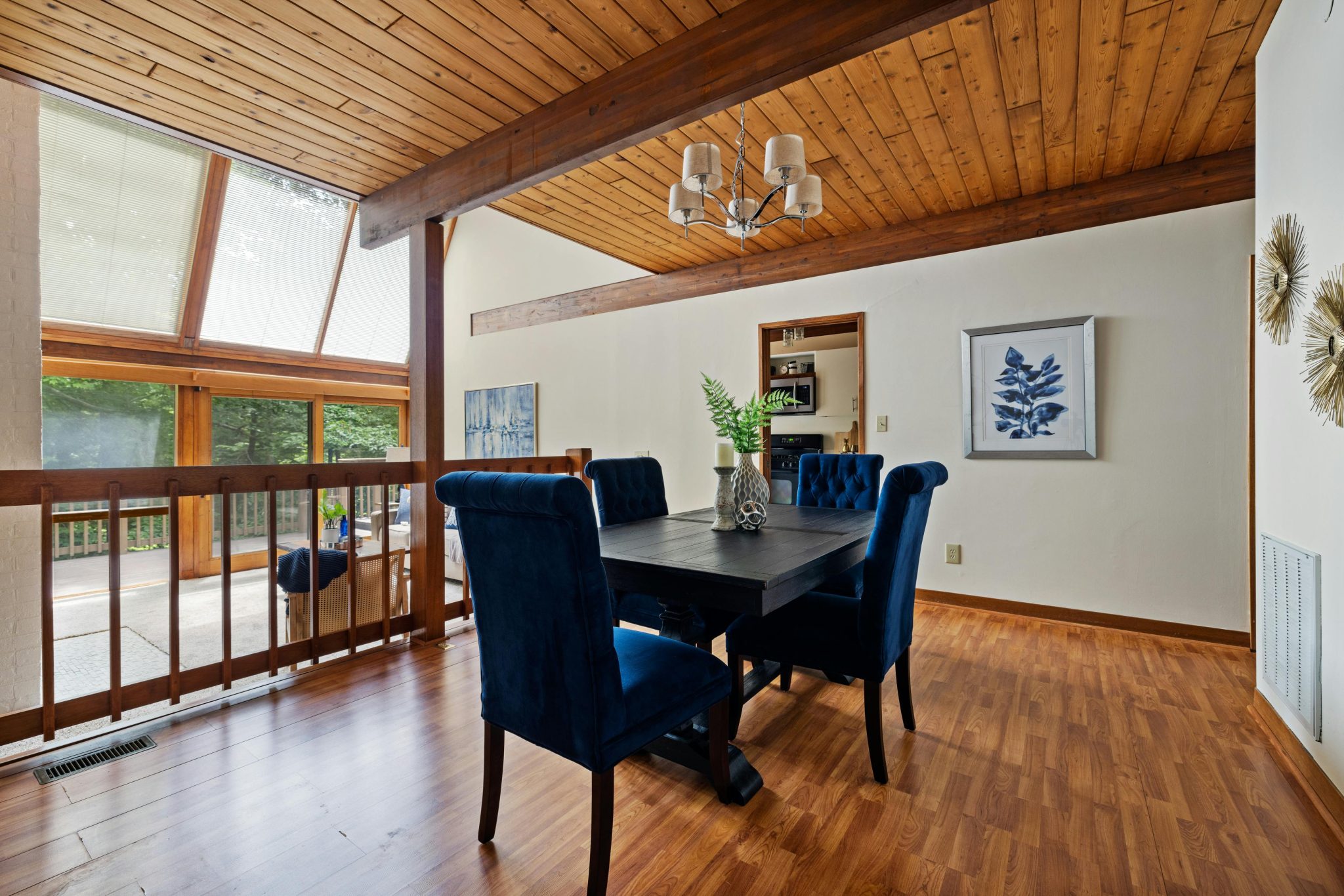 Elegant modern dining room featuring blue chairs, wooden ceiling, and natural light.