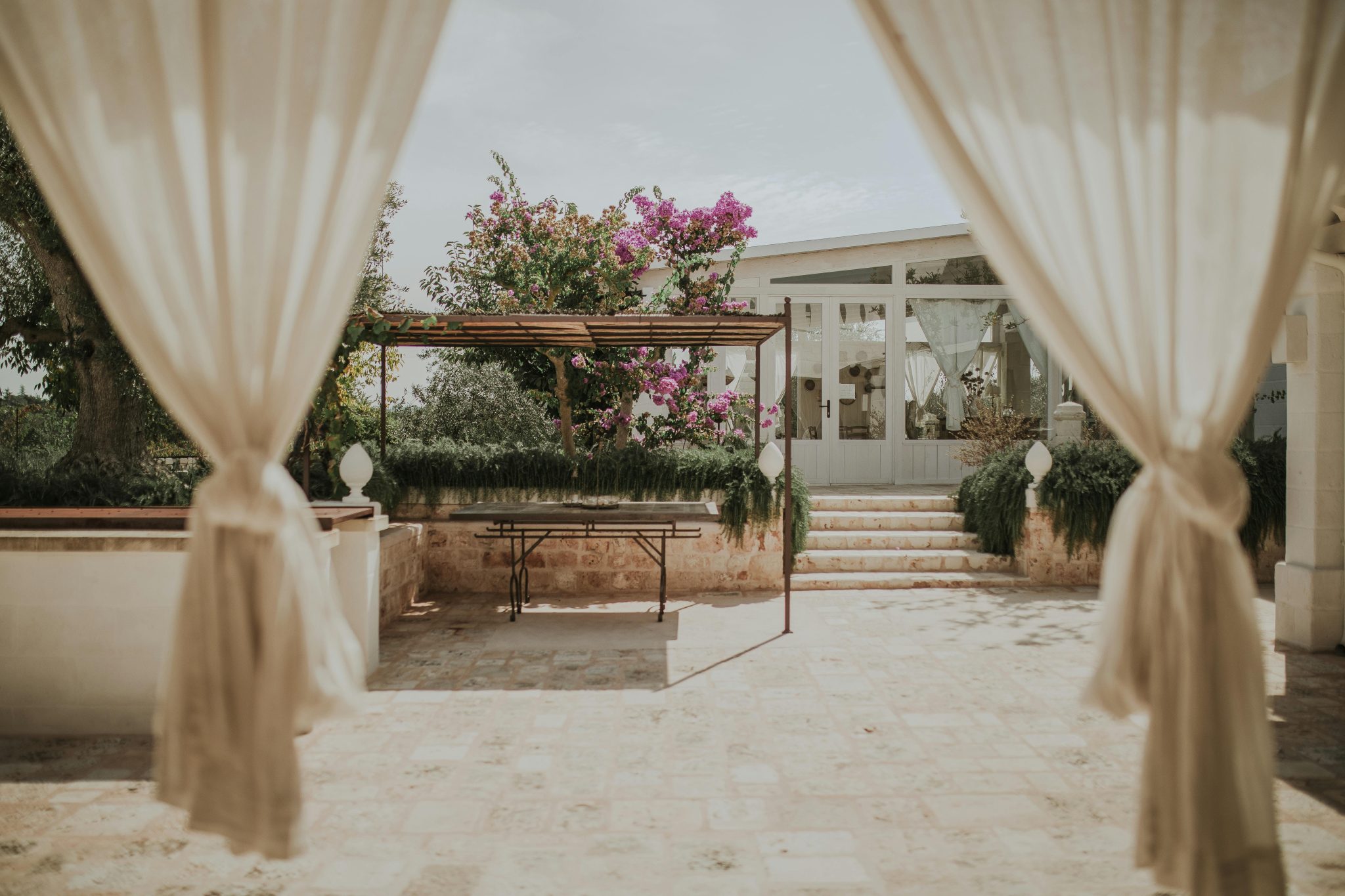 Elegant outdoor gazebo with curtains framing vibrant garden setting.