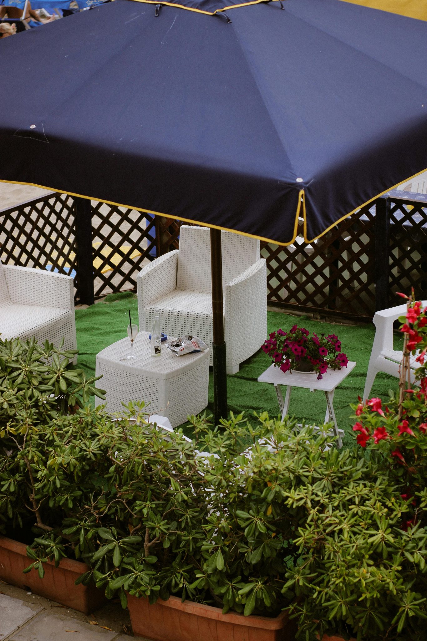 Elegant outdoor seating with white chairs and vibrant flowers under a navy umbrella.