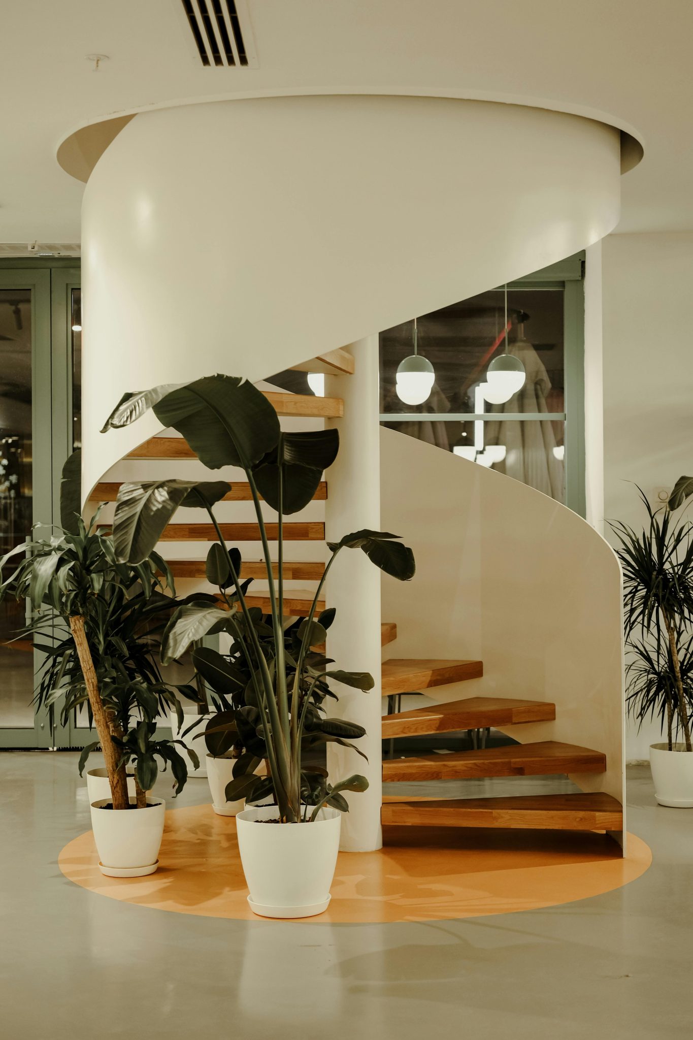 Elegant spiral staircase adorned with indoor plants in a stylish interior setting.