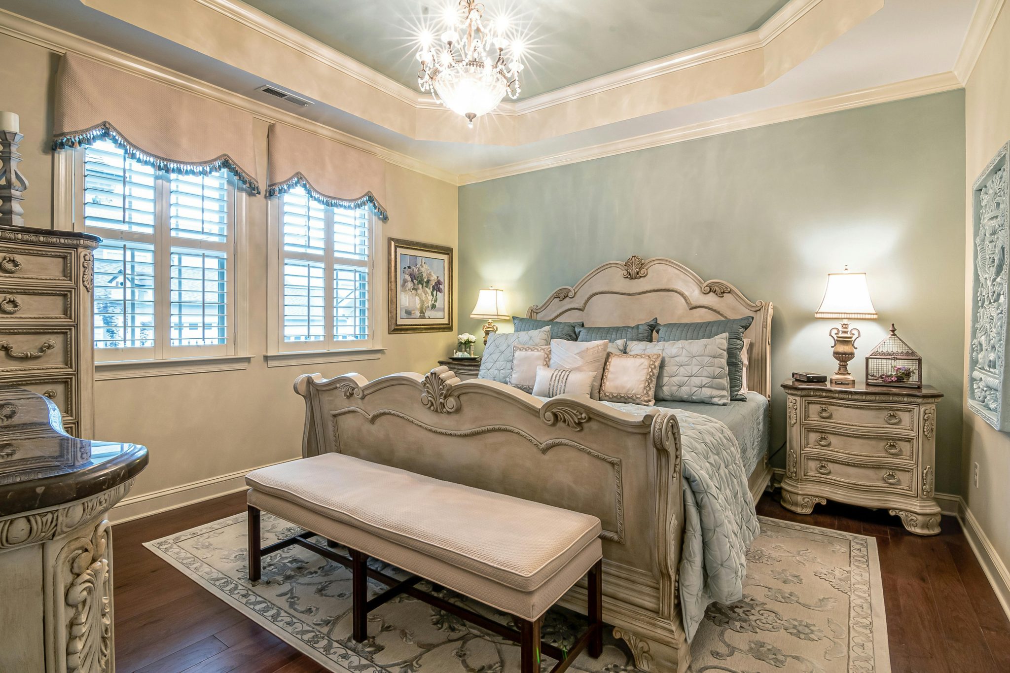 Elegant vintage-style bedroom featuring a classic bed, chandelier, and upscale furnishings.