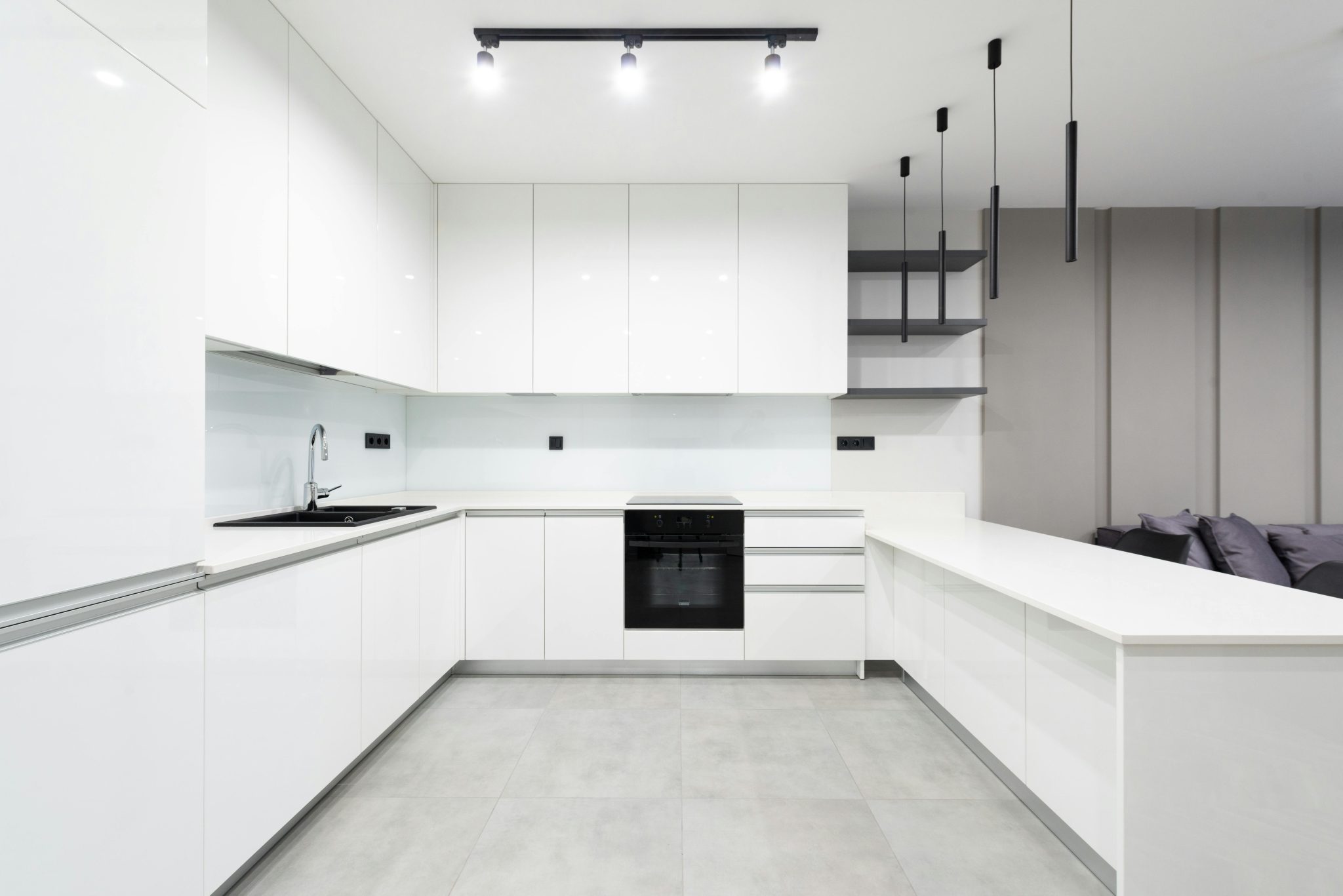 Elegant white minimalist kitchen featuring sleek cabinetry and modern lighting.