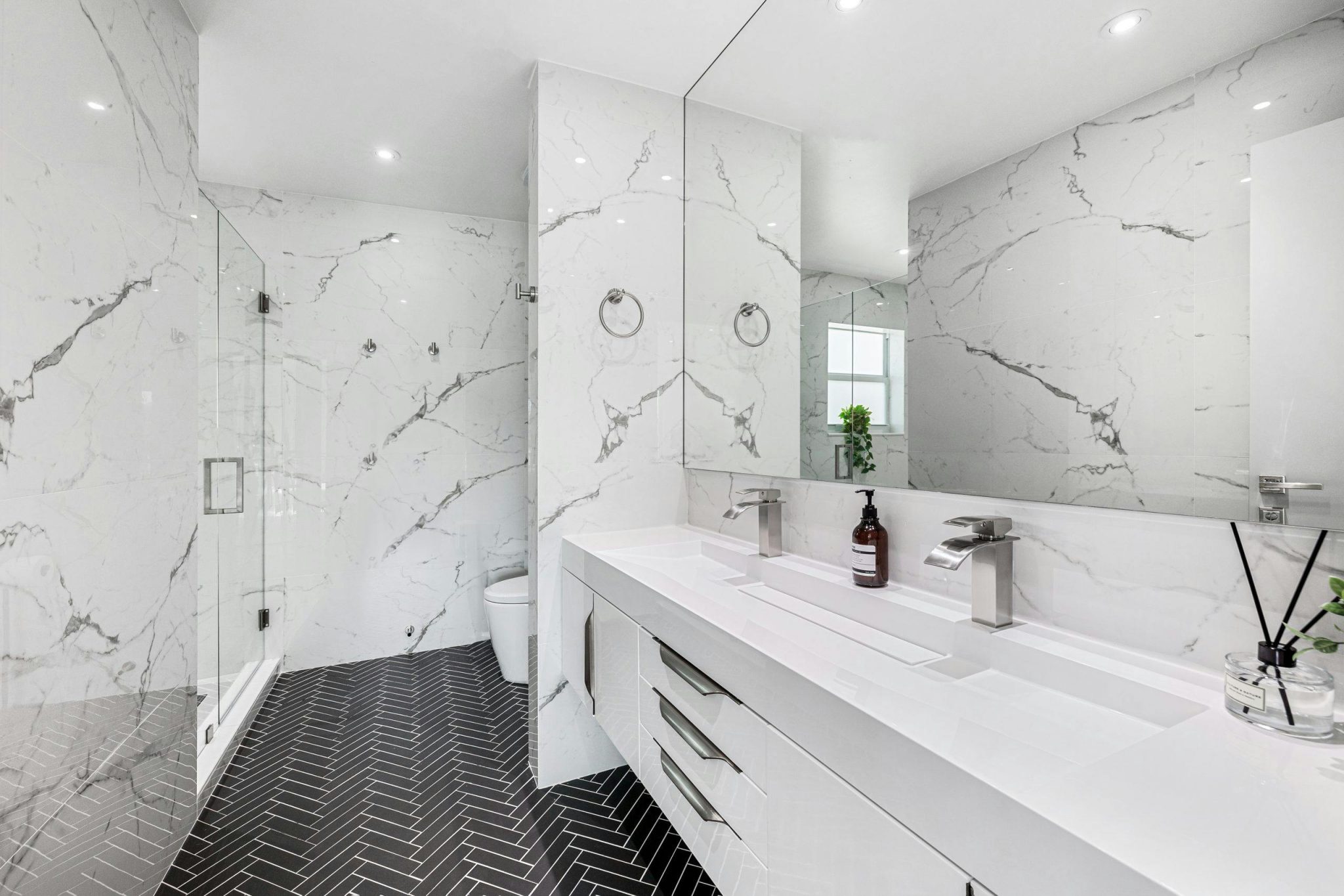 Explore the elegance of a modern bathroom featuring marble walls and sleek fixtures.