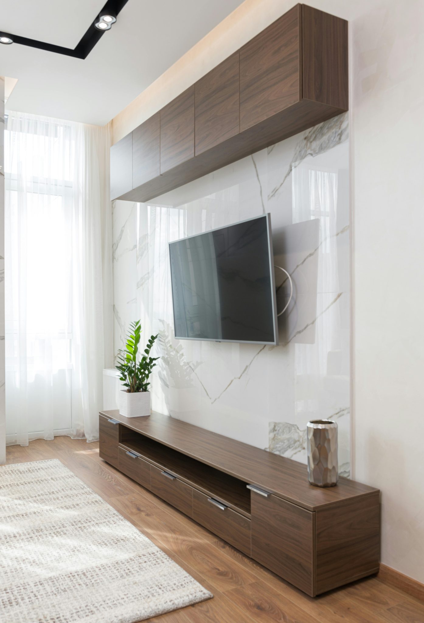 Interior of light living room with carpet on floor TV on wall and cabinet in modern apartment