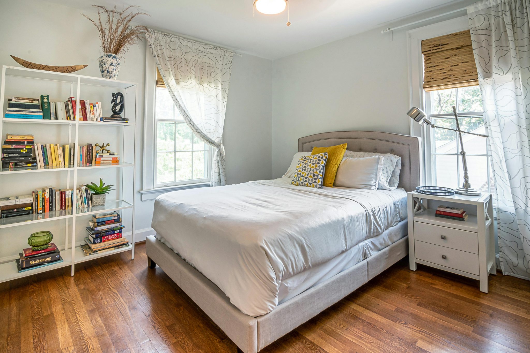 Inviting bedroom interior with modern decor, bookshelf, and soft natural lighting.