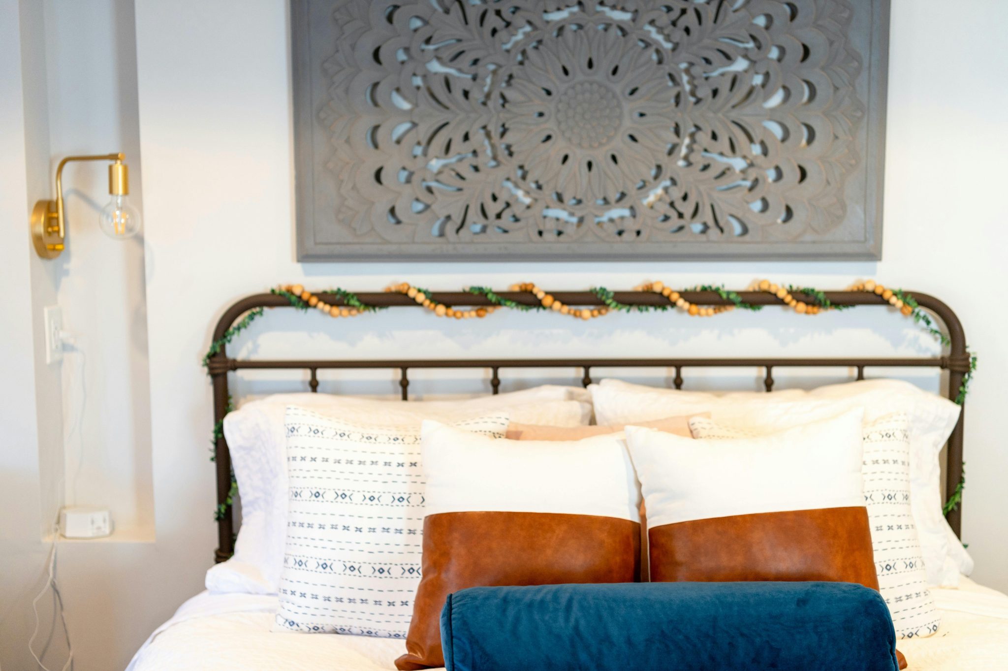 Inviting bohemian-style bedroom with pillows and artistic headboard in Beverly, MA.
