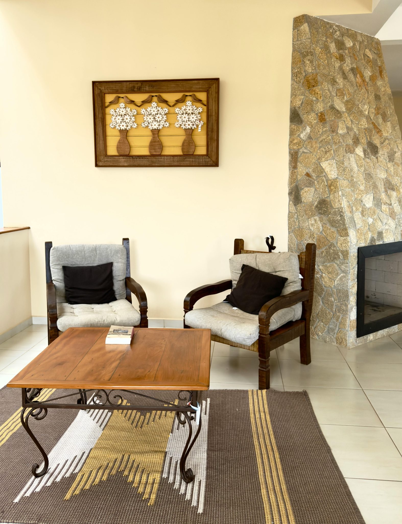 Inviting indoor space featuring rustic furniture, a stone fireplace, and artistic wall decor.