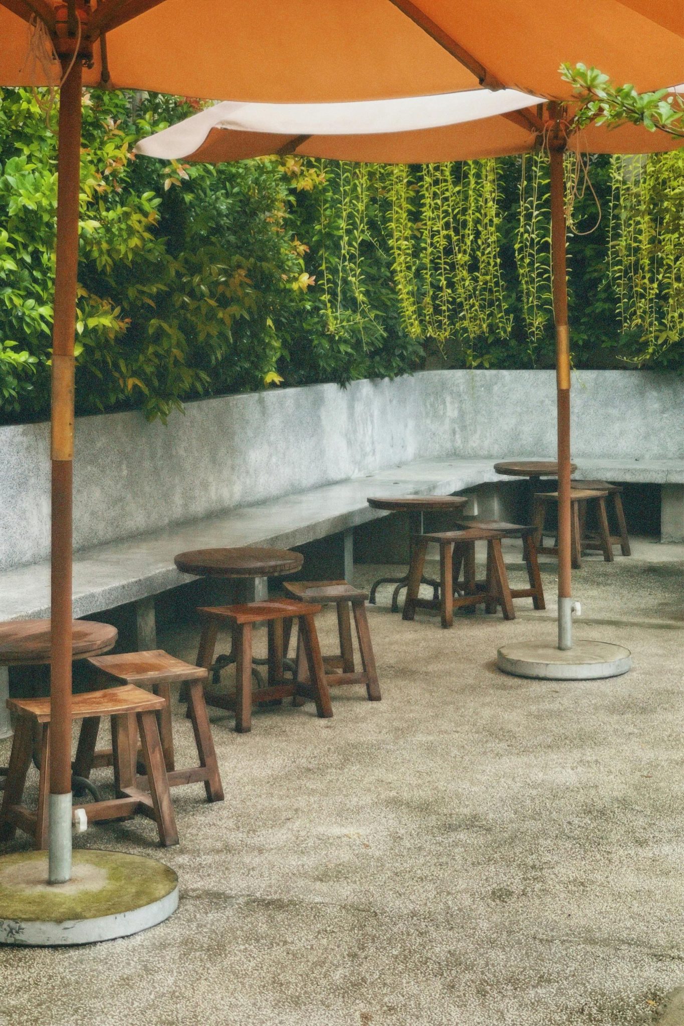 Inviting outdoor patio with wooden tables and chairs under an umbrella, perfect for relaxation.