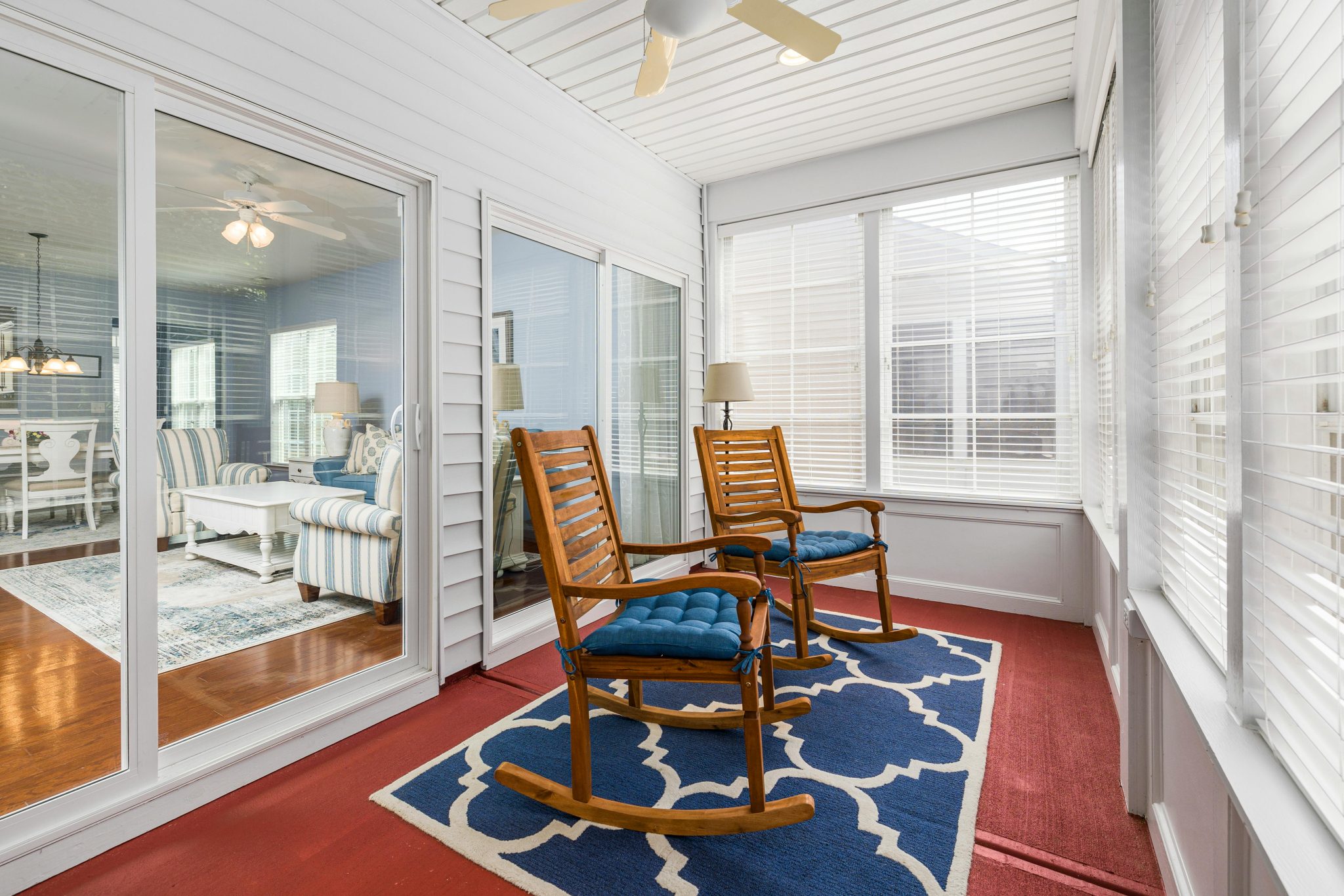 Inviting sunroom with rocking chairs and glass doors leading to a stylish interior living space.