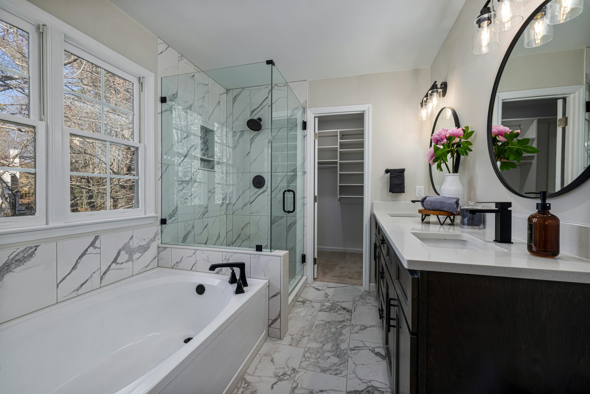 Luxurious bathroom featuring marble tiles, glass shower, and elegant lighting.