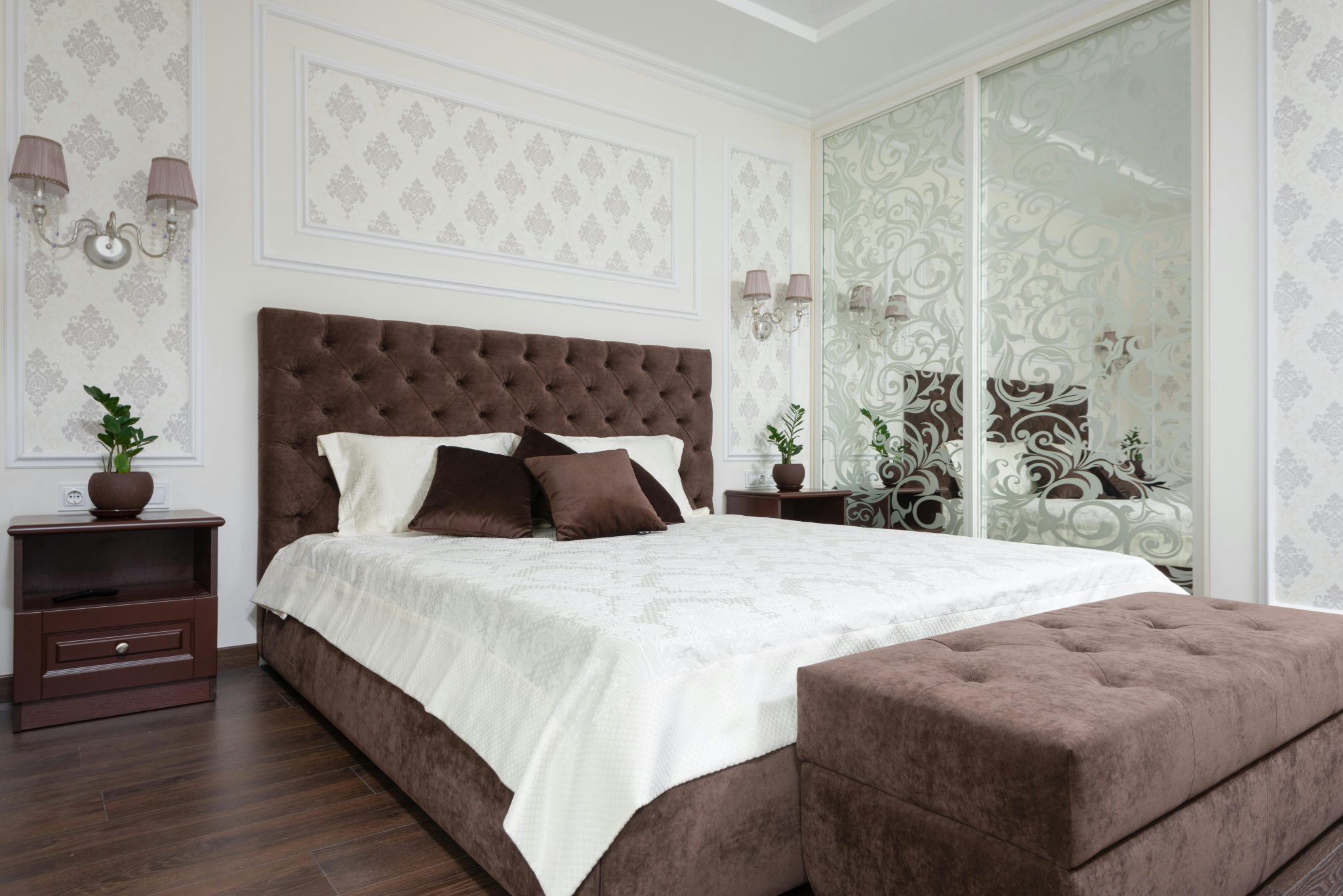 Luxurious bedroom interior with brown tufted headboard and plush ottoman.