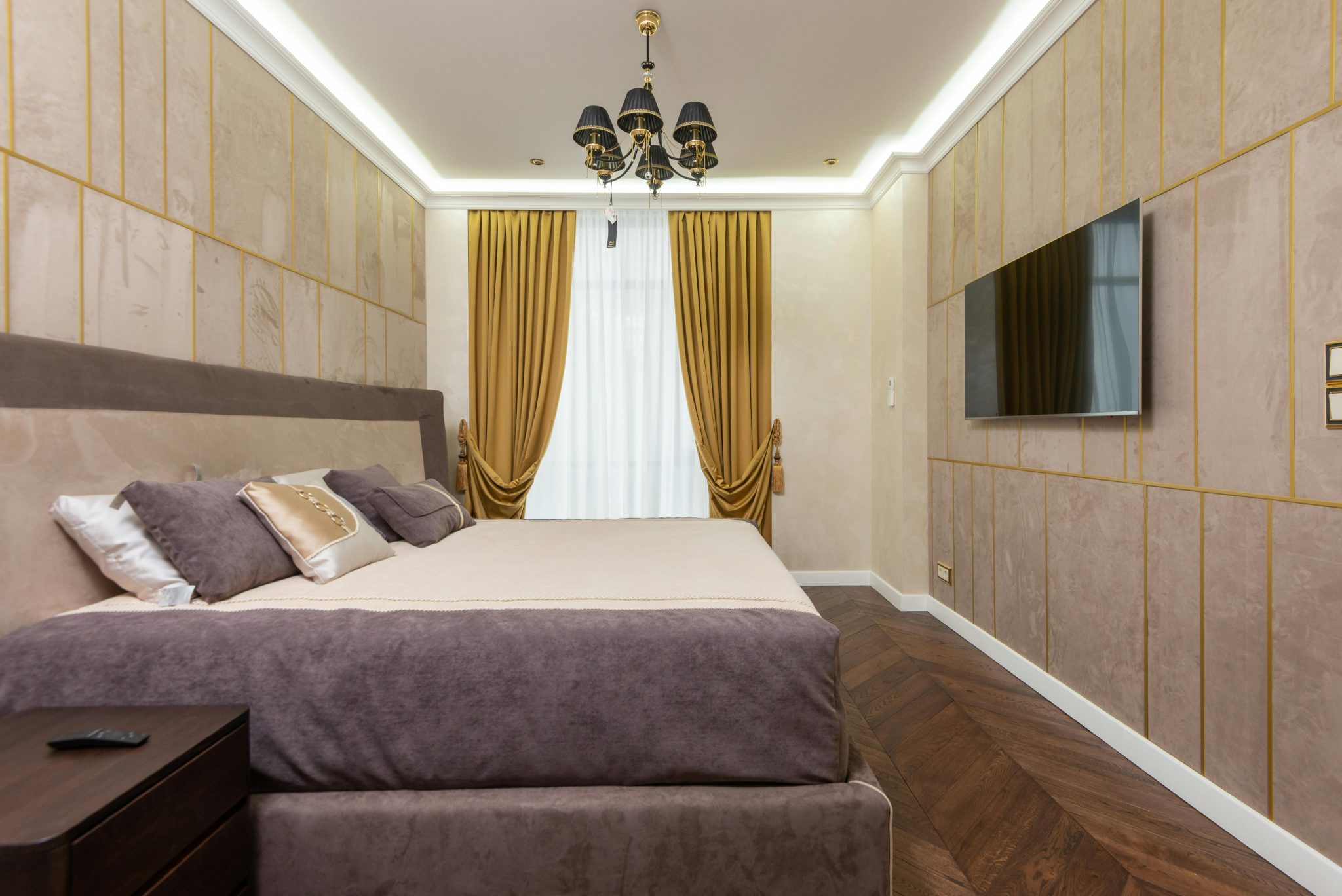Luxurious bedroom with contemporary design, featuring a large bed, chandelier, and wall-mounted TV.