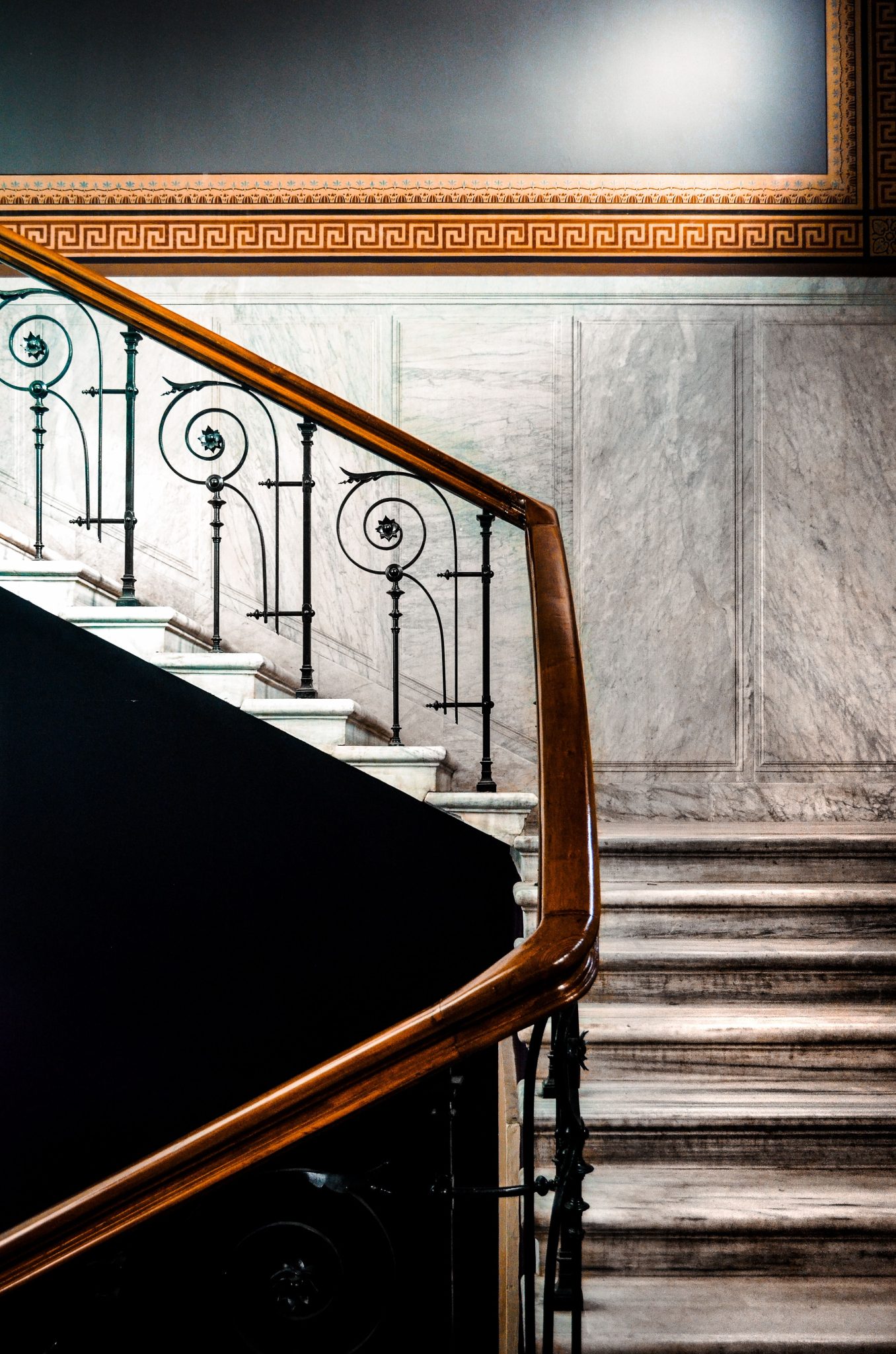 Luxurious marble staircase featuring an intricate iron handrail and classic interior design elements.