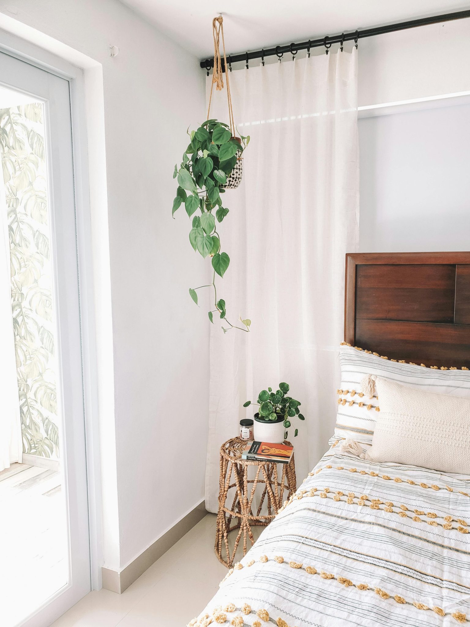 Minimalist bohemian bedroom with cozy decor and lush indoor plants.