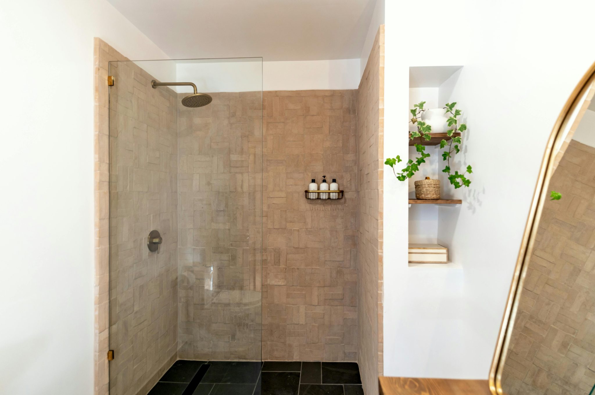 Minimalist Scandinavian bathroom with glass shower and wooden shelves.