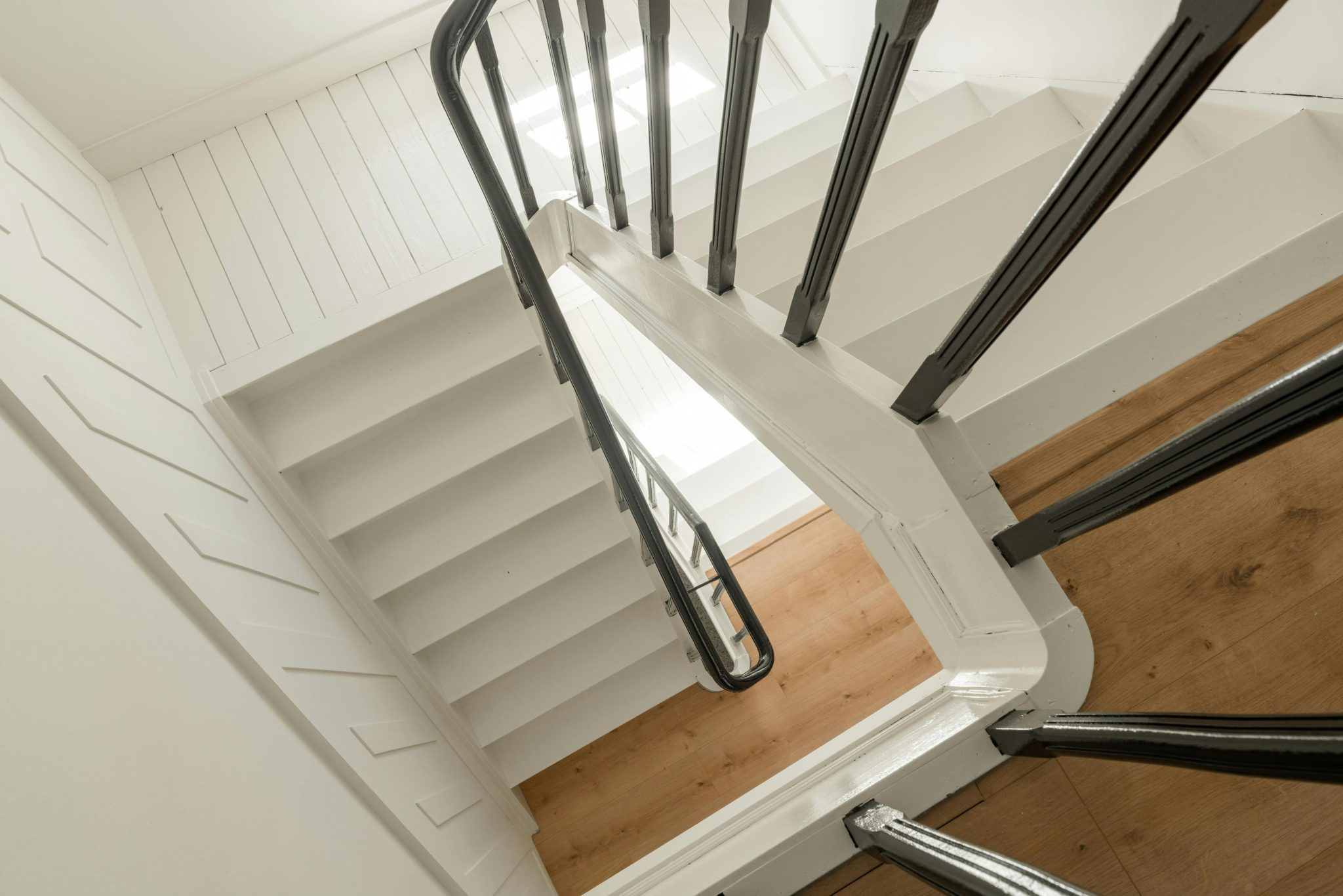 Minimalist view of an interior staircase with wooden steps and metal railings.