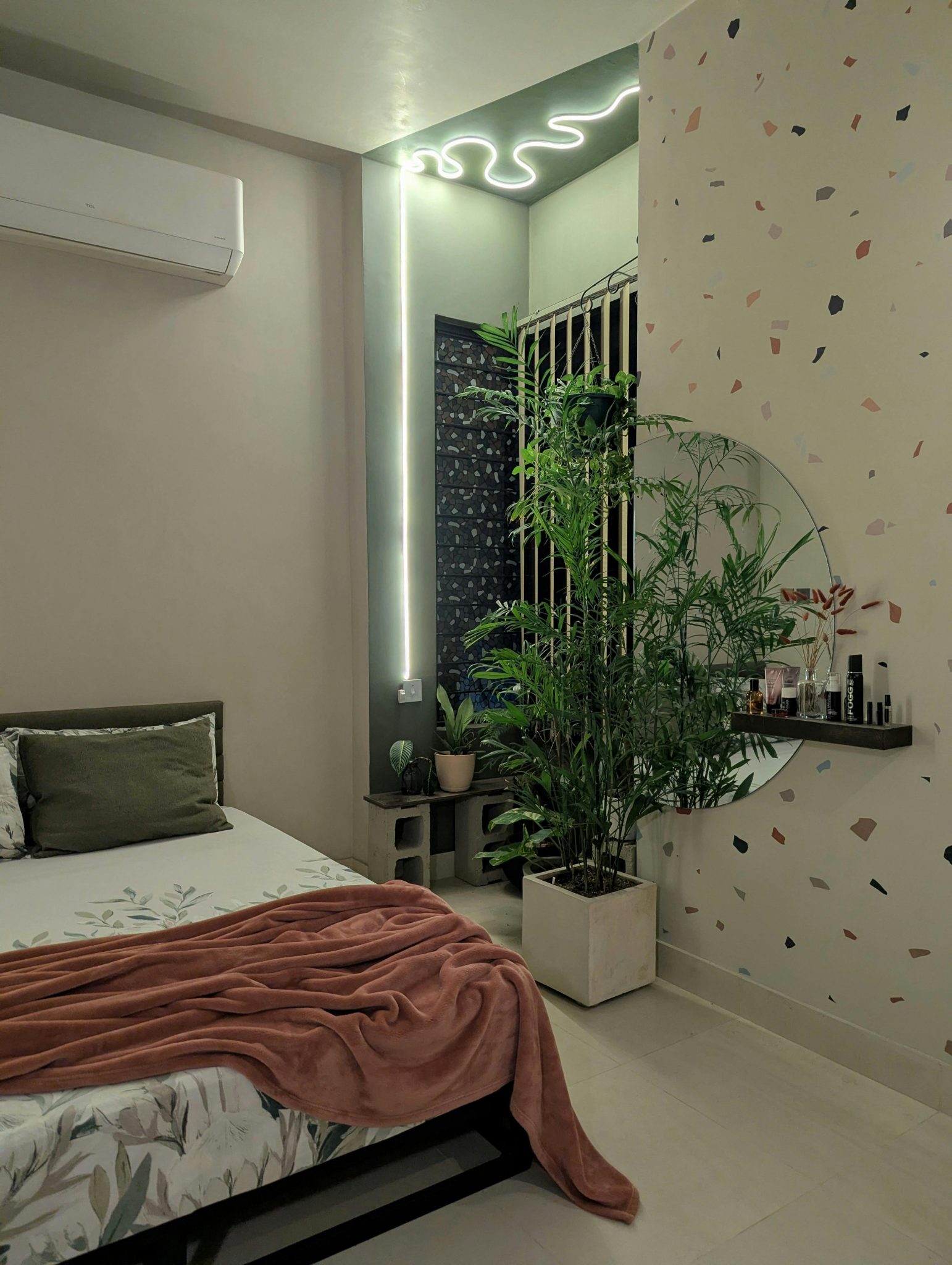 Modern bedroom featuring terrazzo wall, indoor plants, and ambient lighting for a cozy atmosphere.