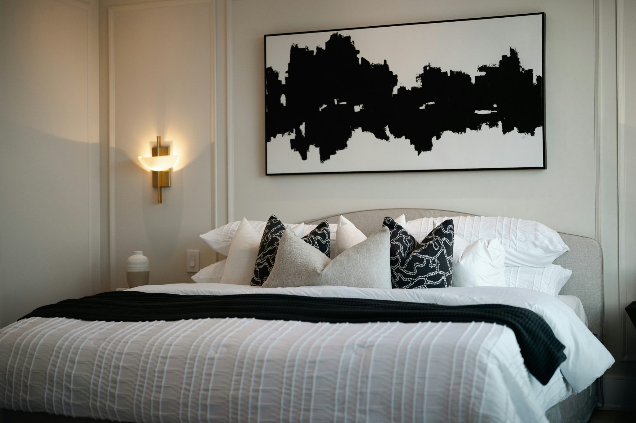 Modern bedroom with abstract art above bed.