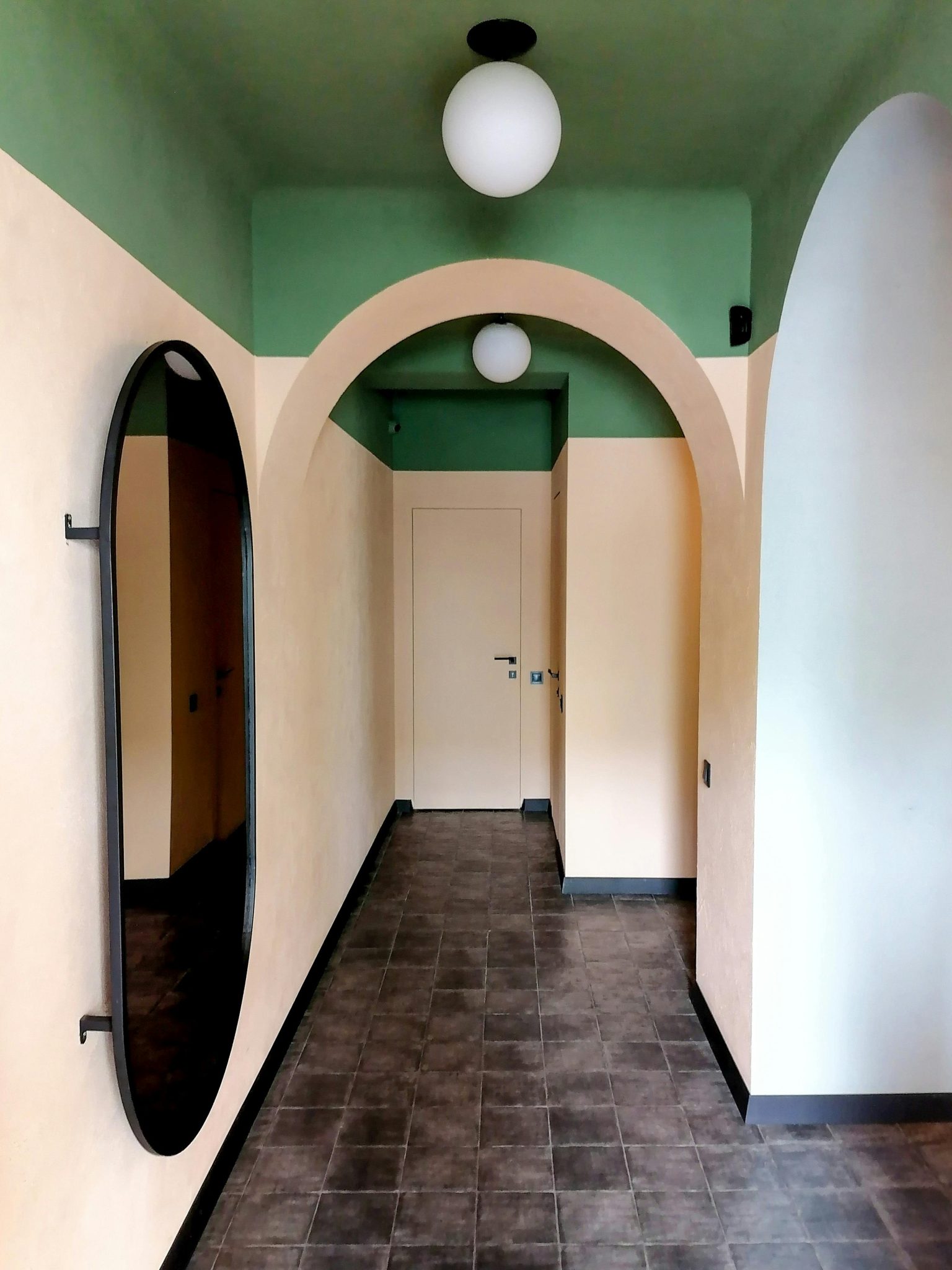 Modern hallway with arched design, mirror reflection, and stylish lighting.