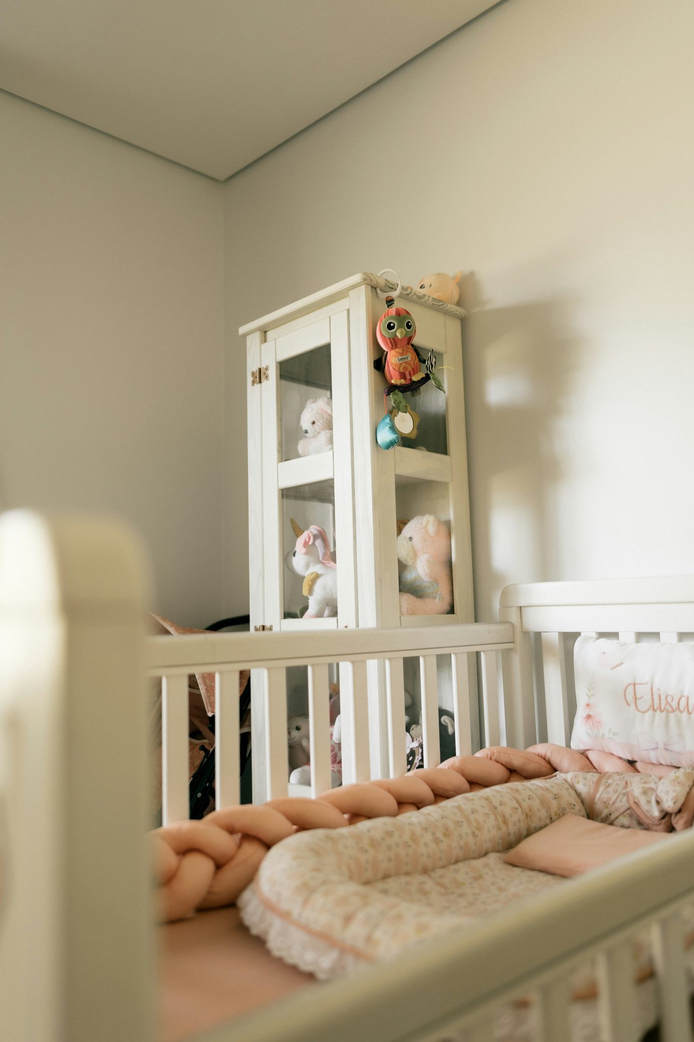 Nursery with crib and stuffed animals on shelf.