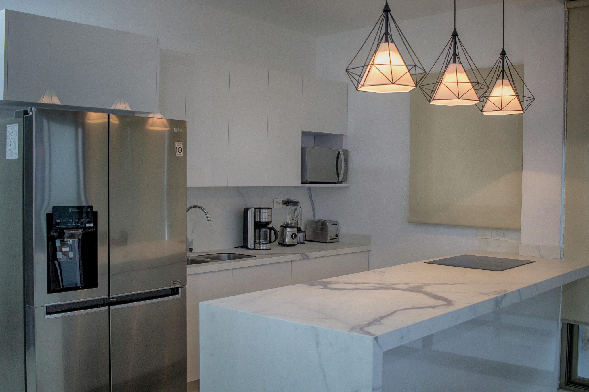 Sleek kitchen design with marble countertop, stainless steel appliances, and pendant lighting.