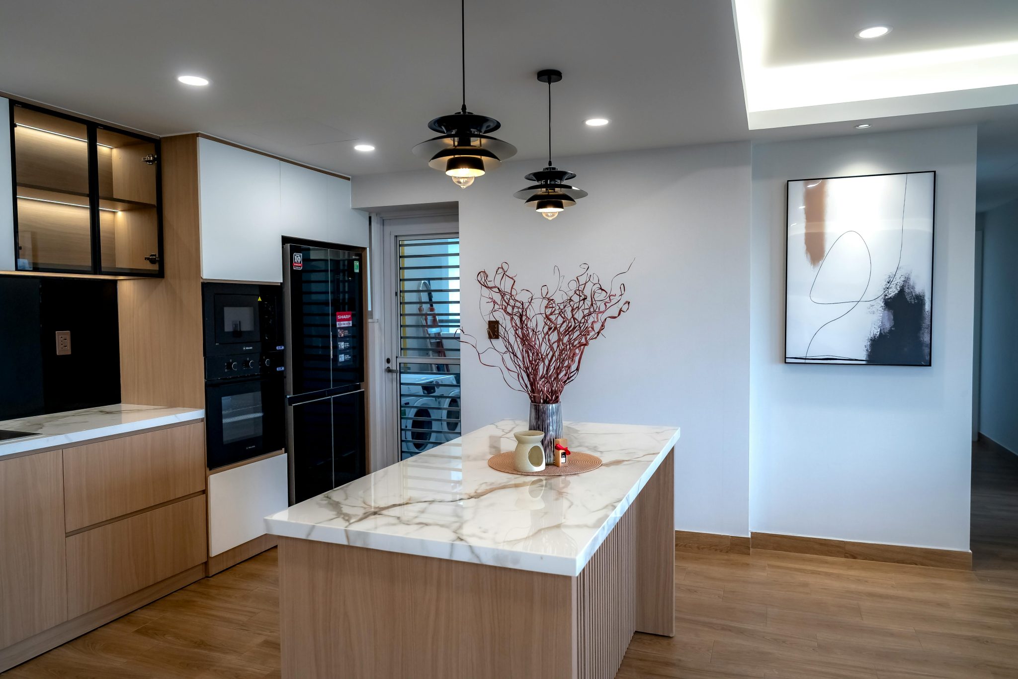 Sleek modern kitchen featuring a marble island, pendant lighting, and minimalist design.