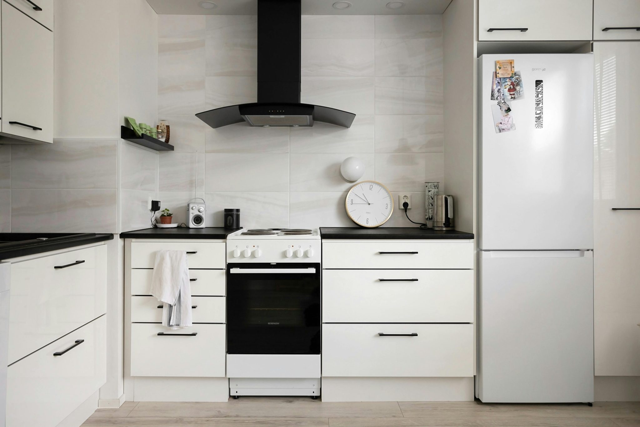 Sleek modern kitchen with white cabinets, stove, and fridge, showcasing minimalist interior design.