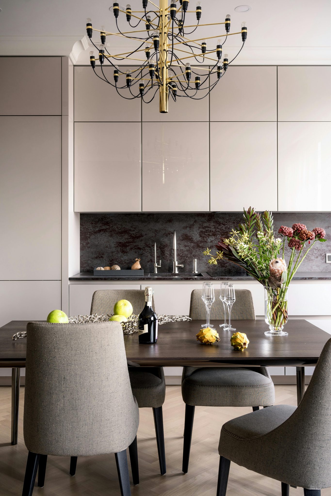 Sophisticated dining space featuring modern chairs, a chandelier, and a floral arrangement.