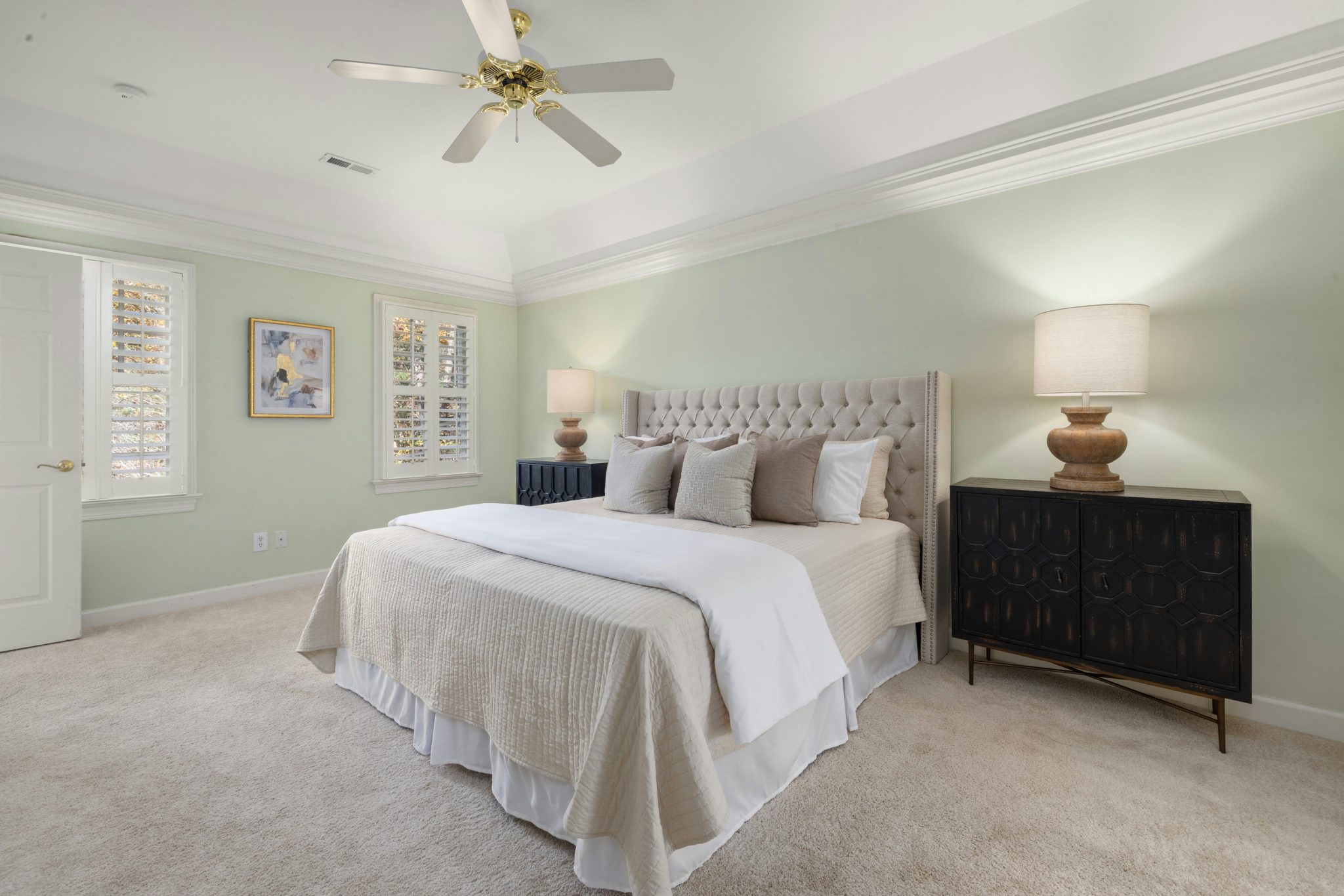 Spacious bedroom with cozy bed, modern decor, and ceiling fan.