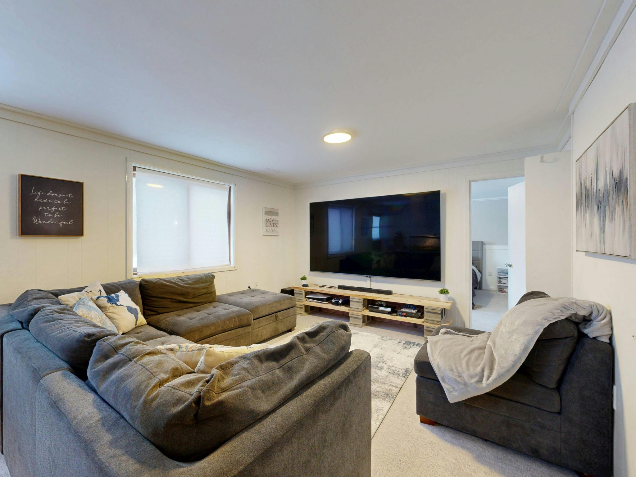 Spacious living room featuring a large flat-screen TV, gray sectional sofa, and cozy decor.