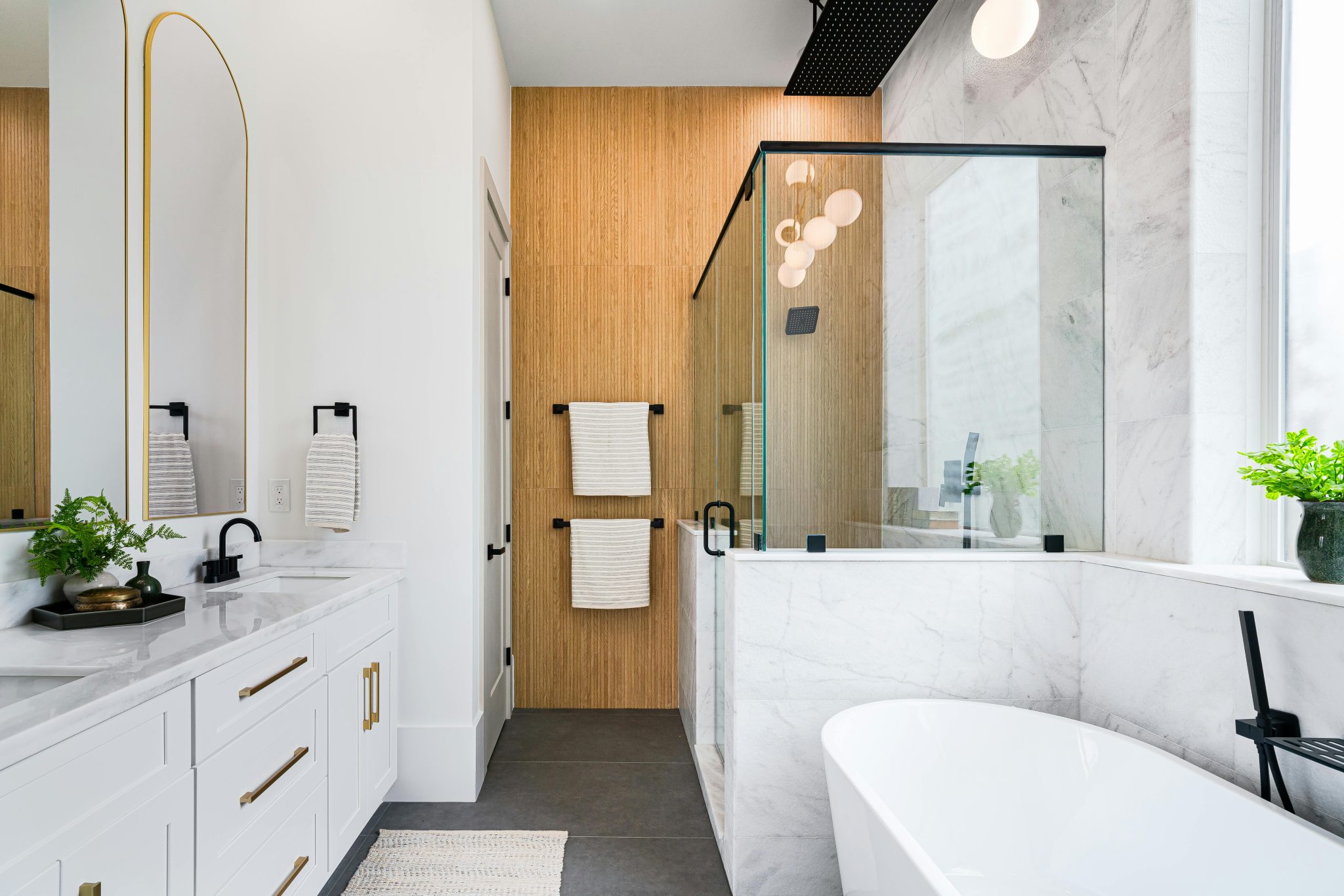 Spacious modern bathroom with marble, glass shower and elegant fixtures.