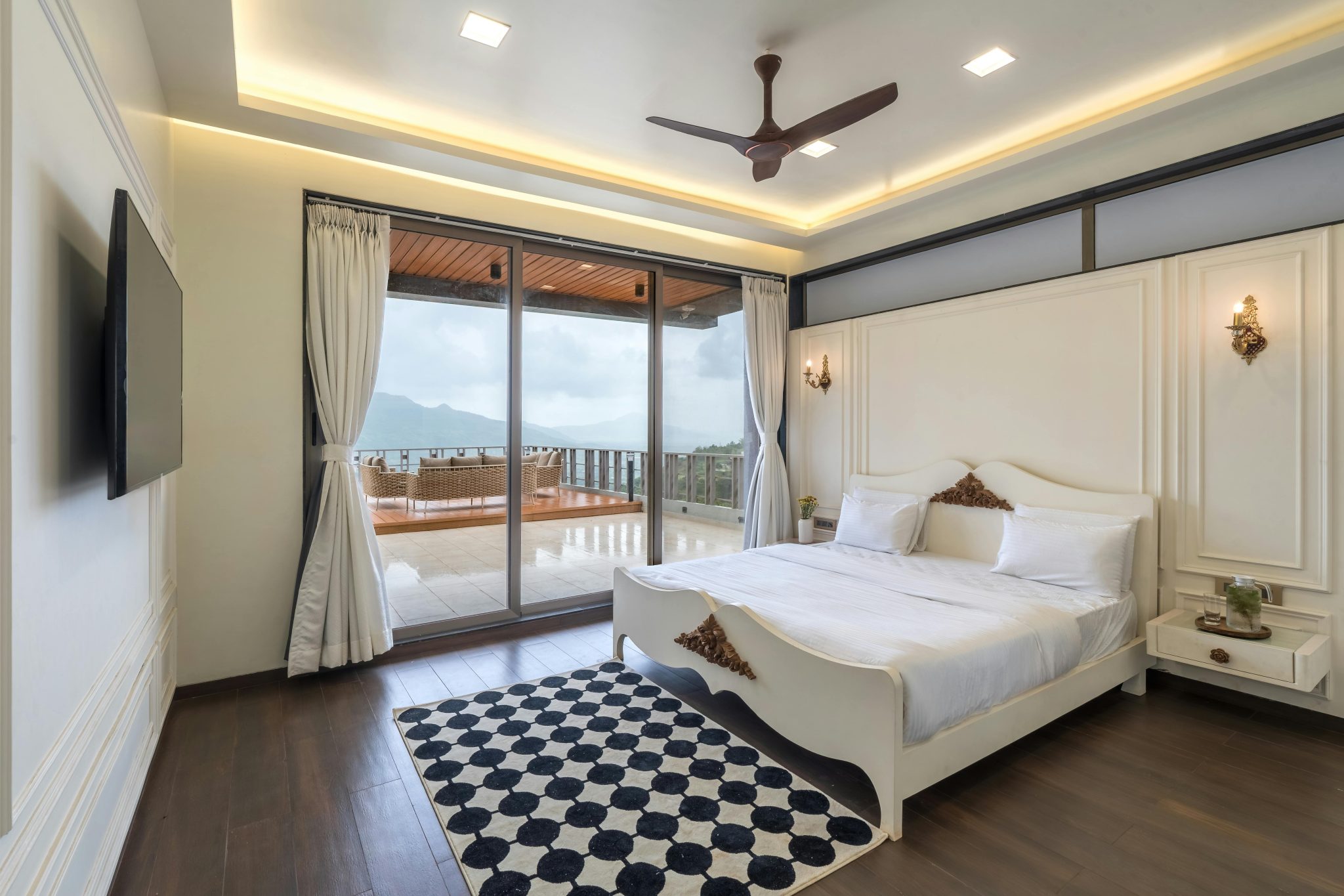 Spacious modern bedroom featuring a double bed, checkered rug, and scenic balcony view, perfect for luxury living.