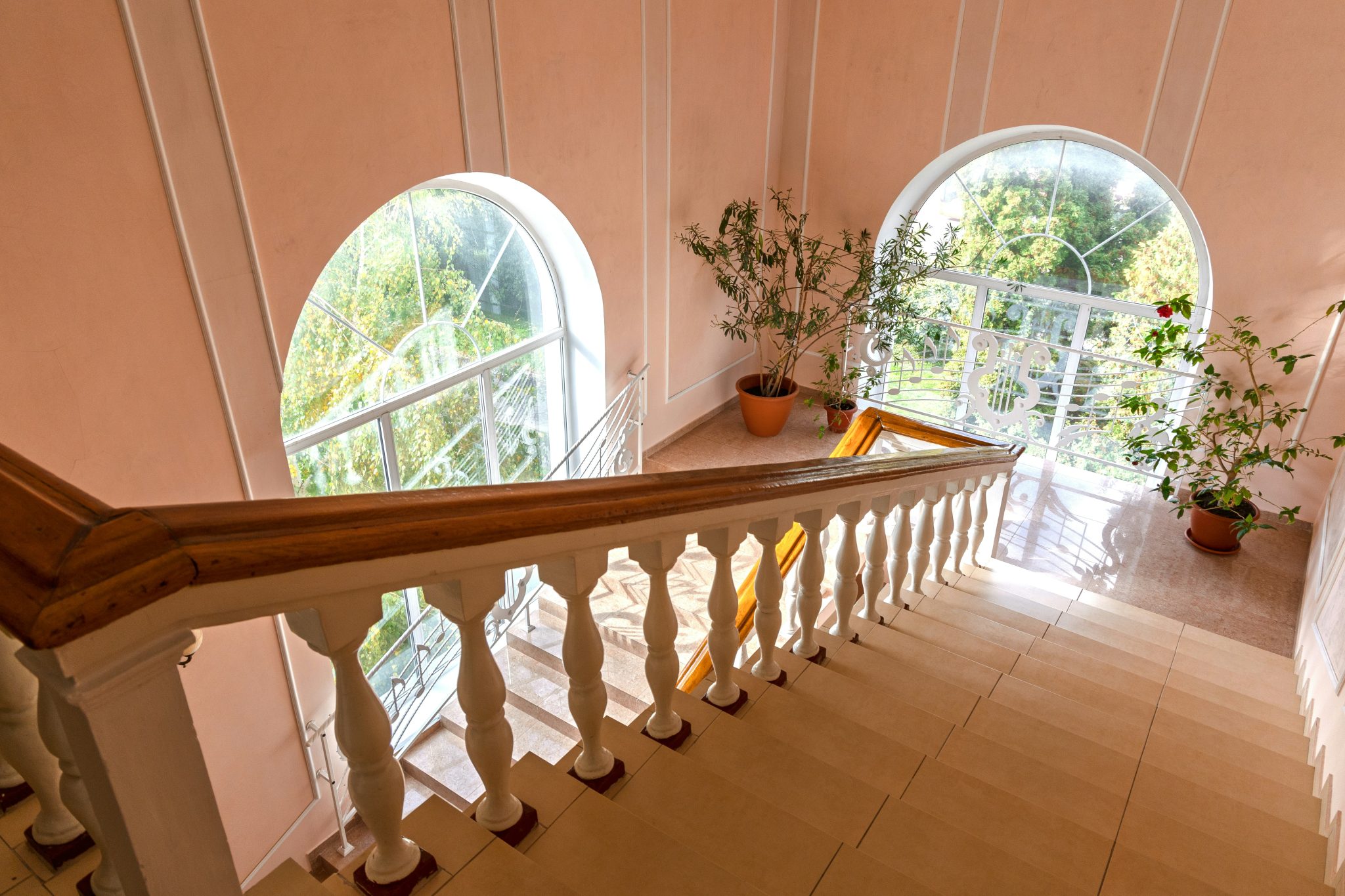 Staircase with ornate railing and arched windows
