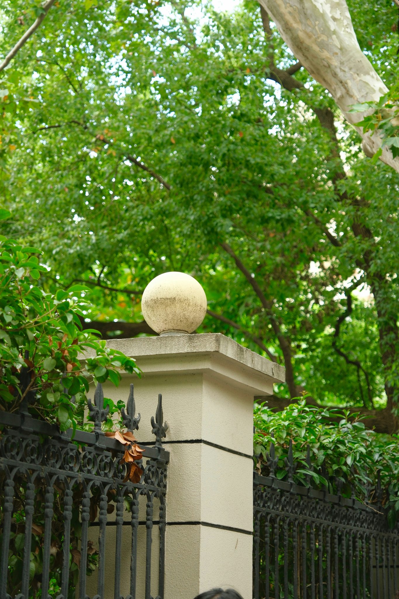 Stone sphere atop a pillar beside a decorative metal fence.