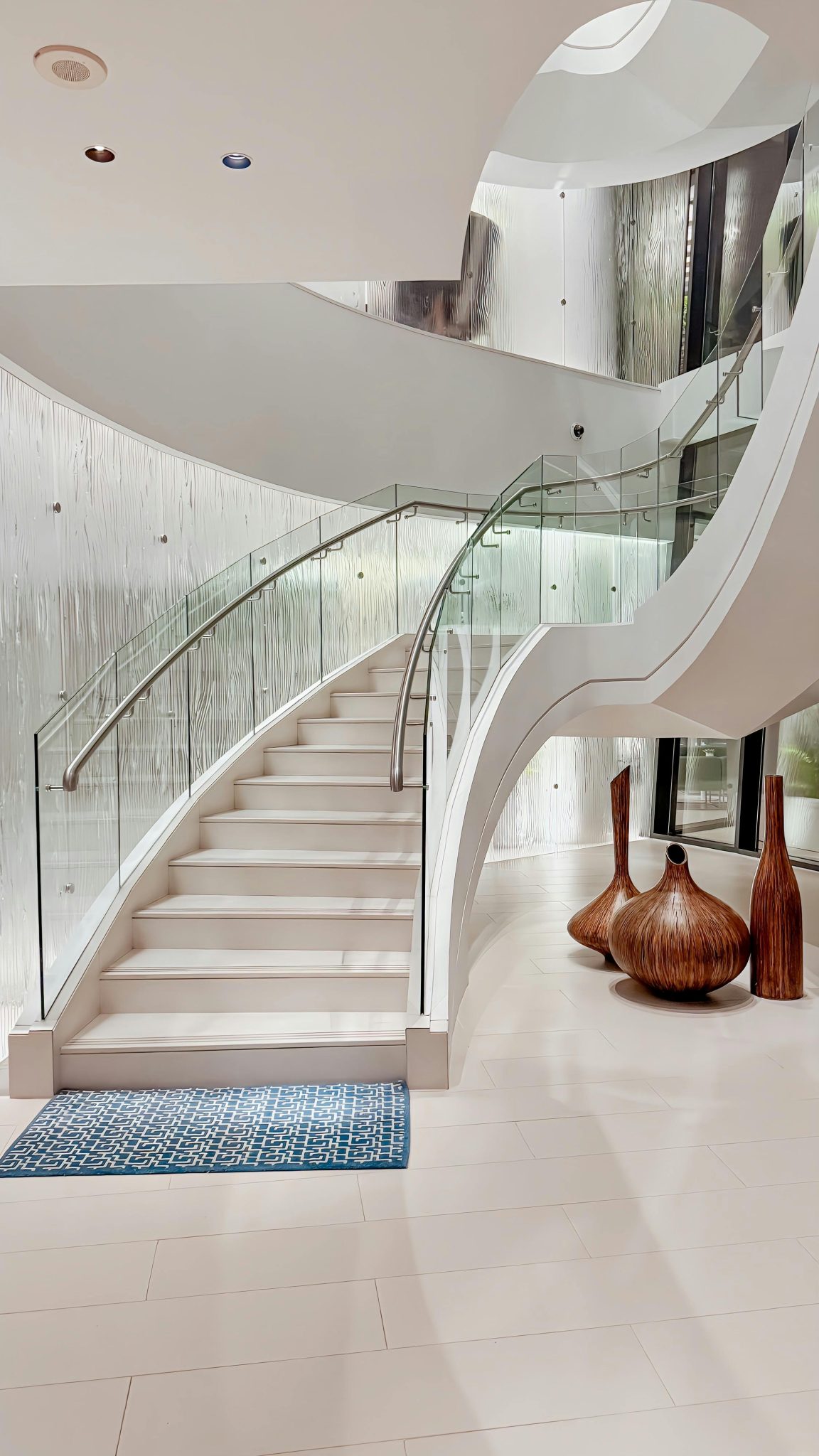 Stunning spiral staircase with glass railing in a luxurious Abu Dhabi home interior.